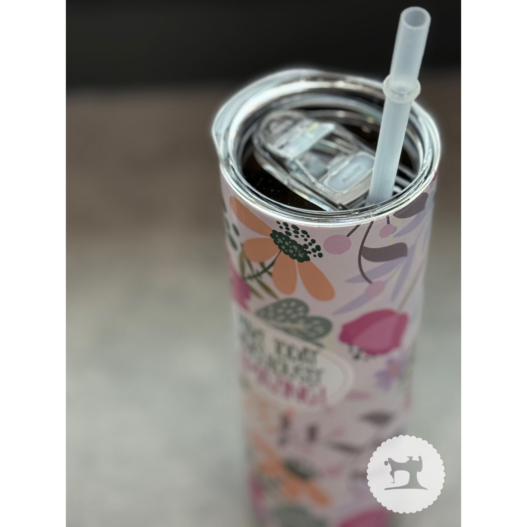 Colorful tumbler with floral design and straw on a neutral background