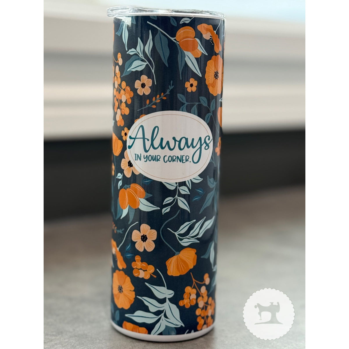 Tumbler with floral design and 'Always in your corner' text on a neutral background