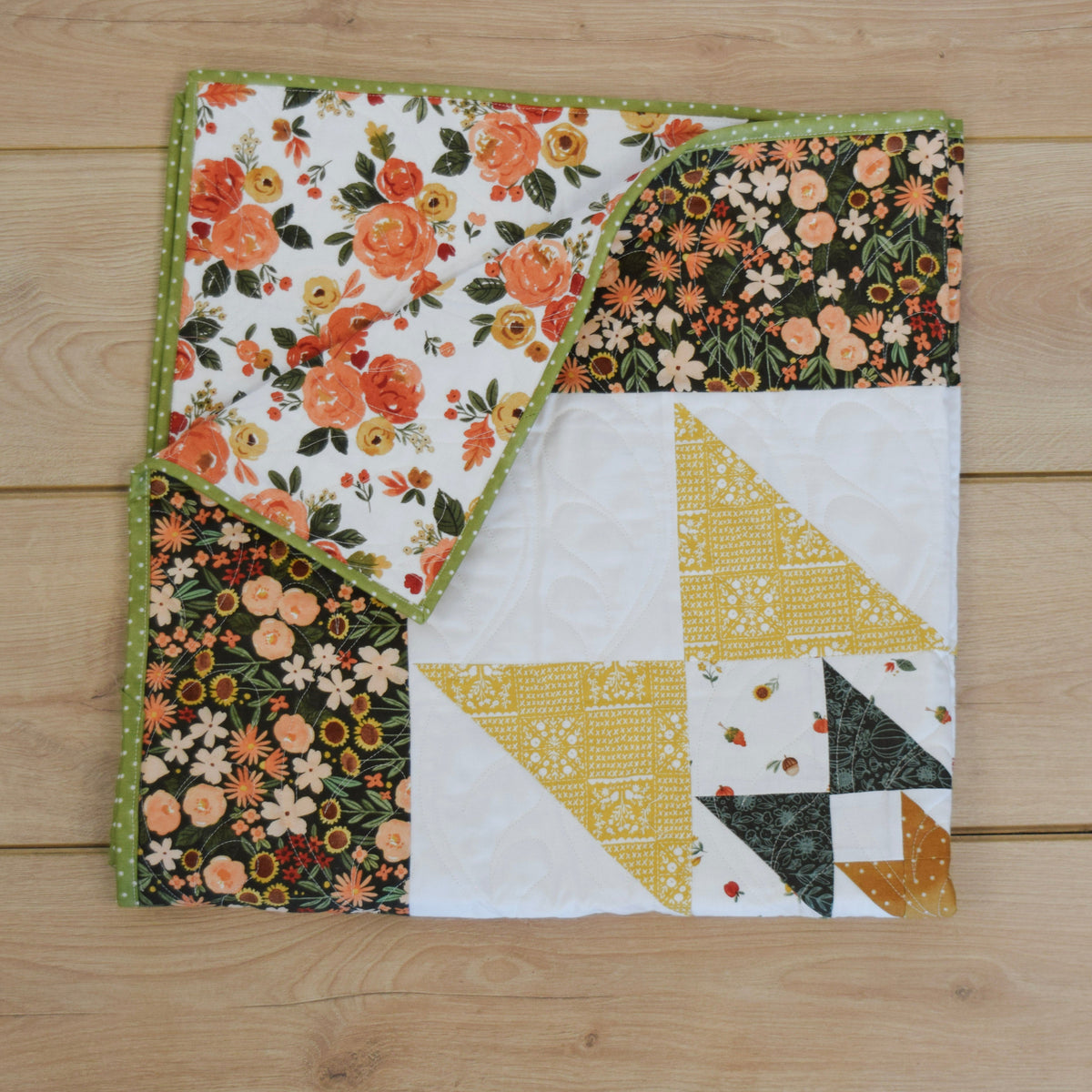 Quilt with floral and geometric patterns on a wooden surface