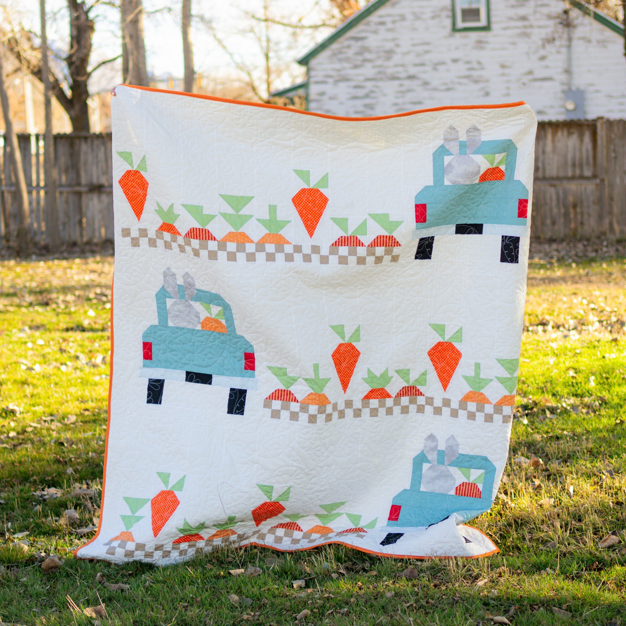 Quilt with truck and carrot pattern on grass