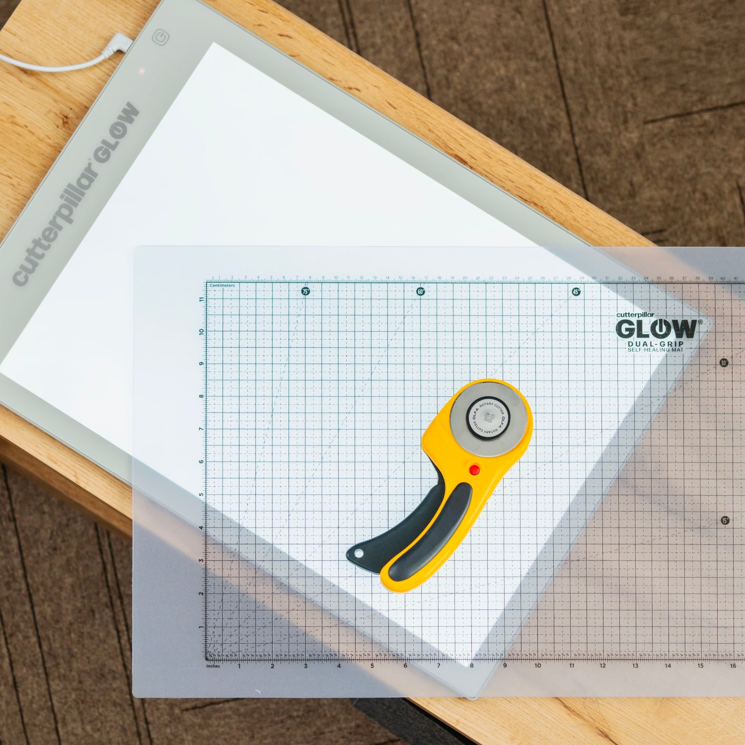 Cutterfuls Glow cutting mat with a rotary cutter on a wooden surface