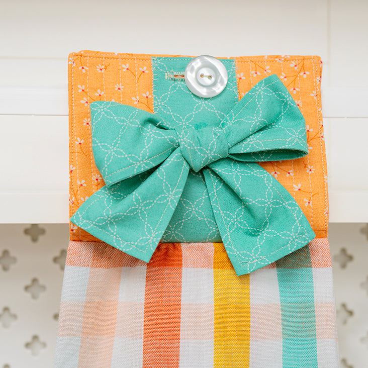 Fabric square with a green bow and button on an orange background