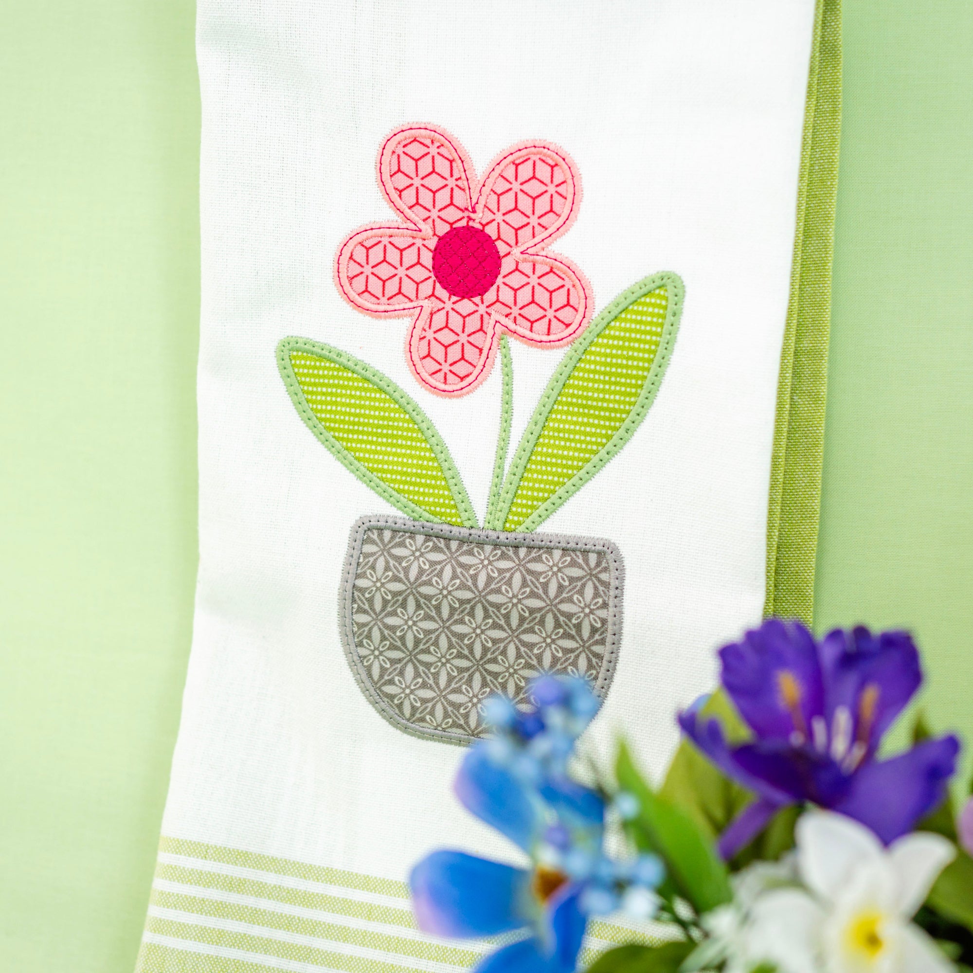 Embroidered flower design on a white fabric with a green background