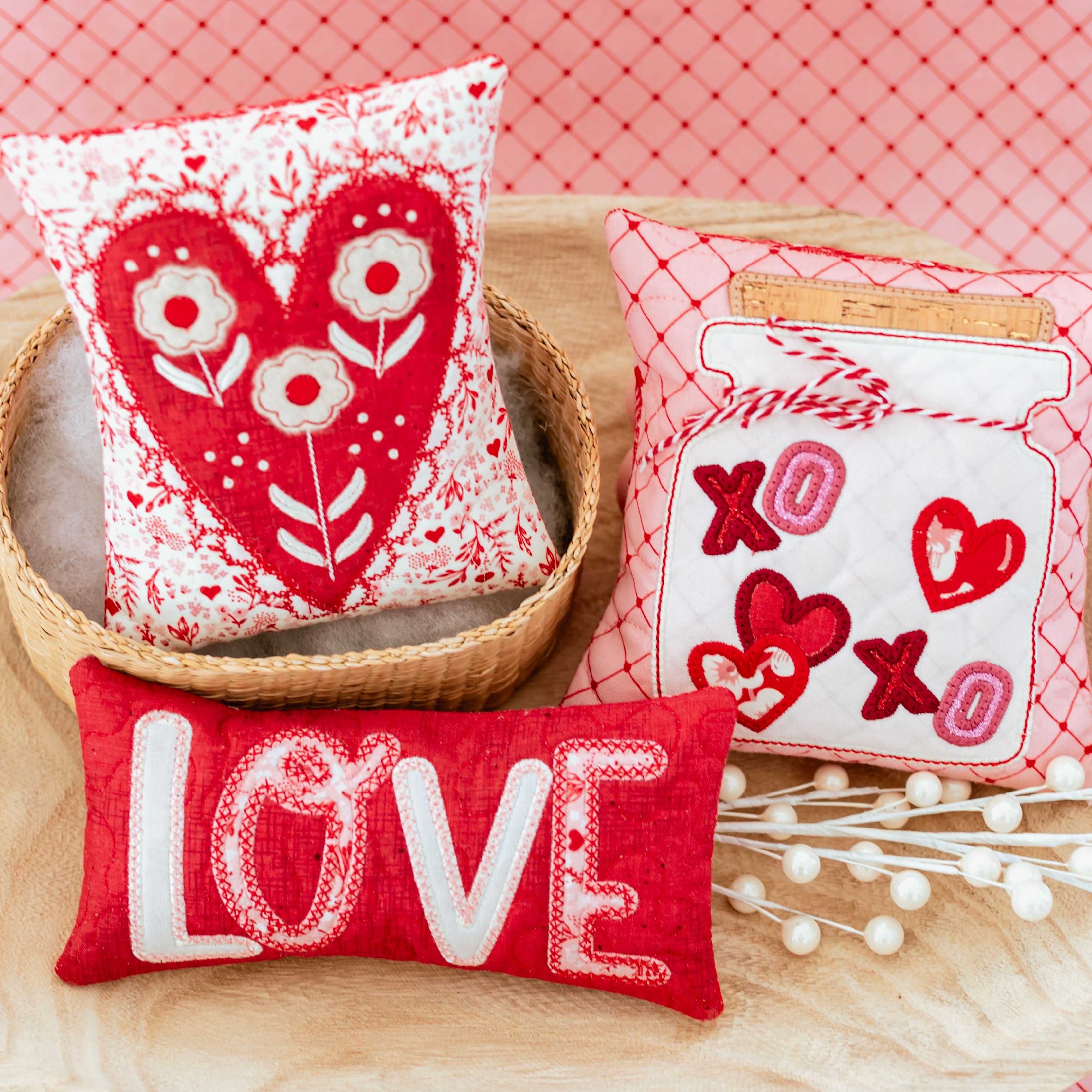 Three decorative pillows with heart and 'LOVE' designs on a red checkered background.