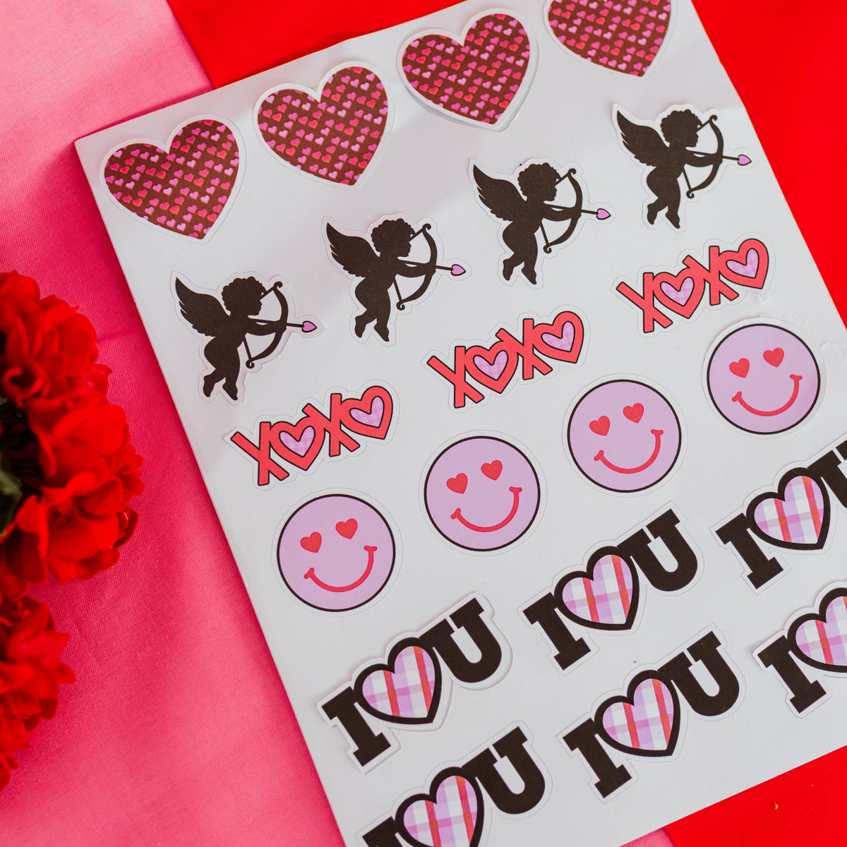 Sheet of stickers with hearts, cupids, and 'I love you' text on a red background.