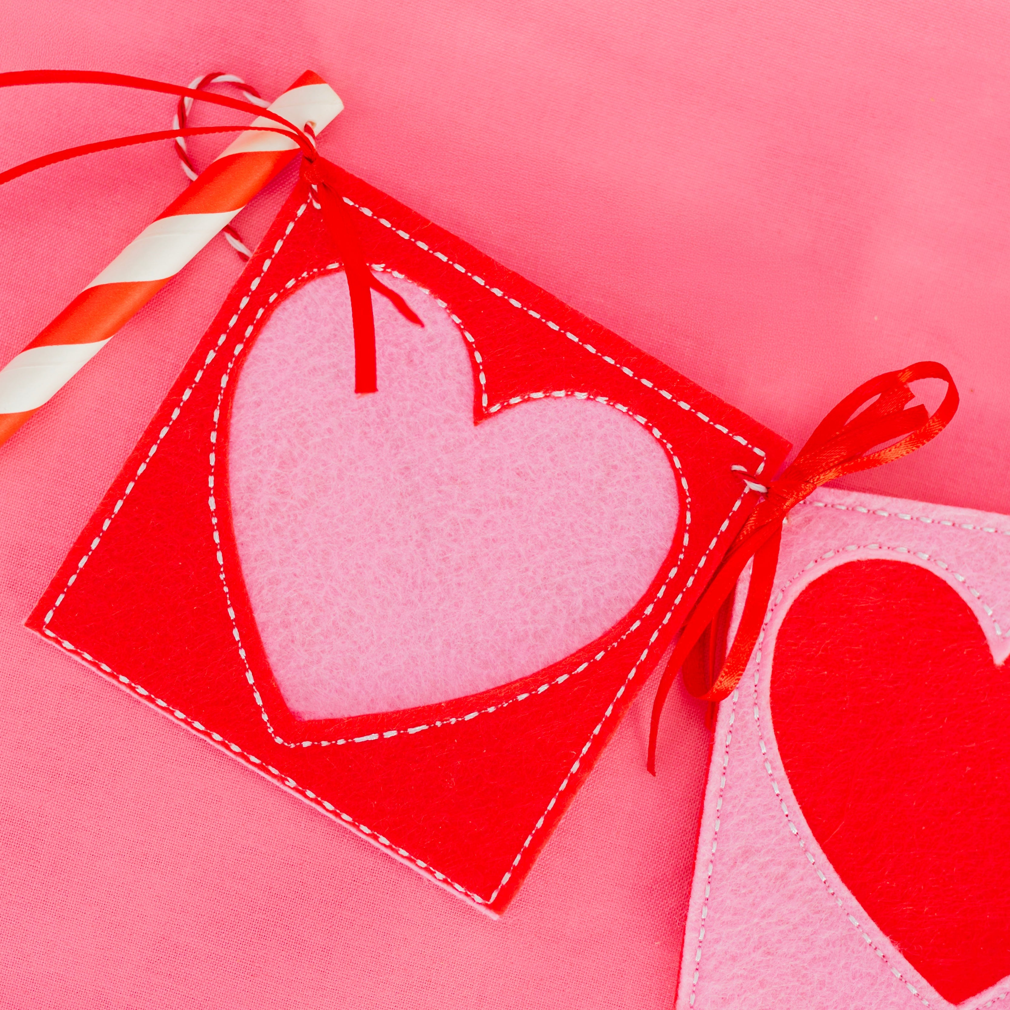 Heart-shaped gift tag with a straw on a pink background