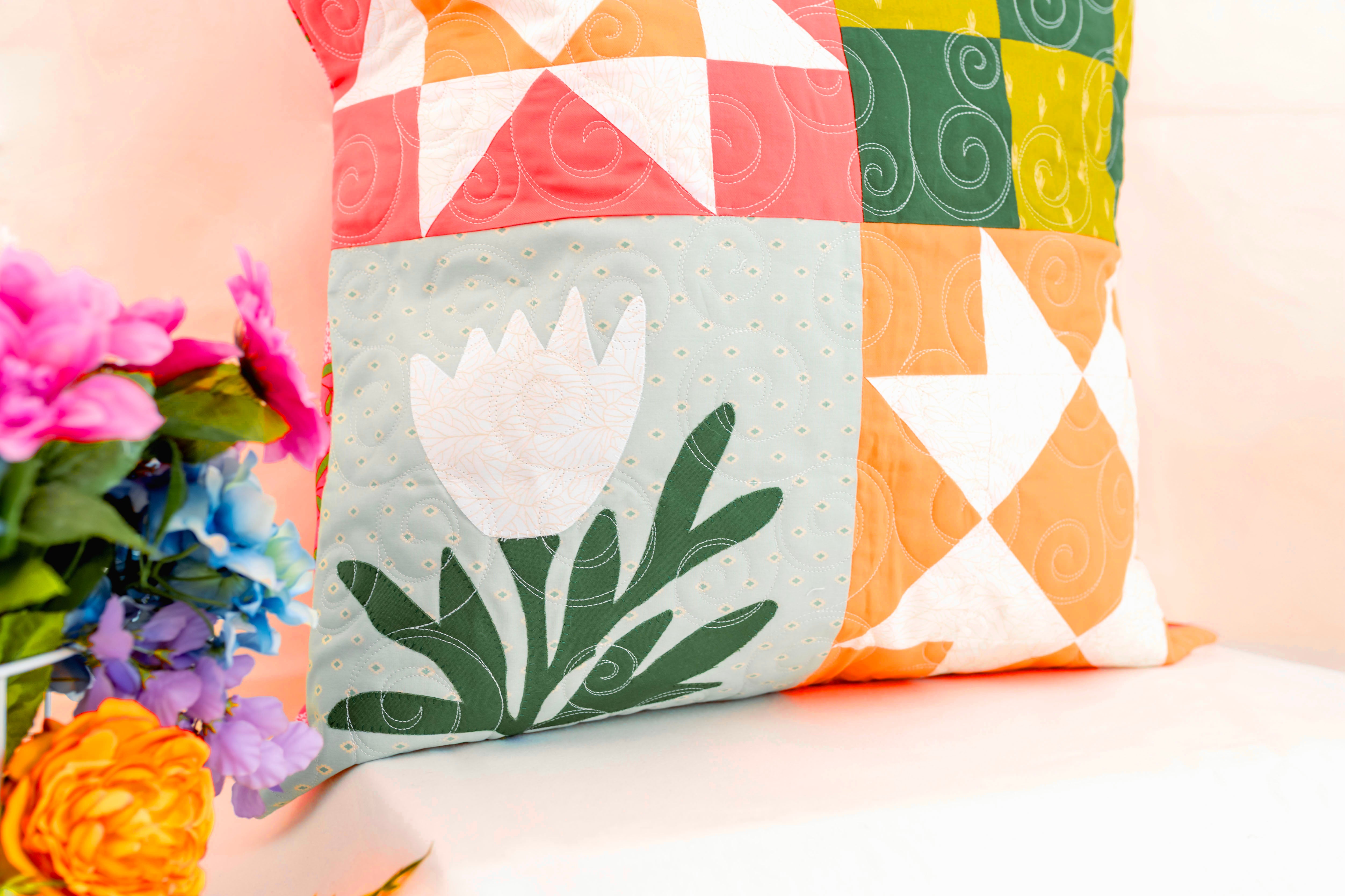 Colorful quilted pillow with floral design on a light background