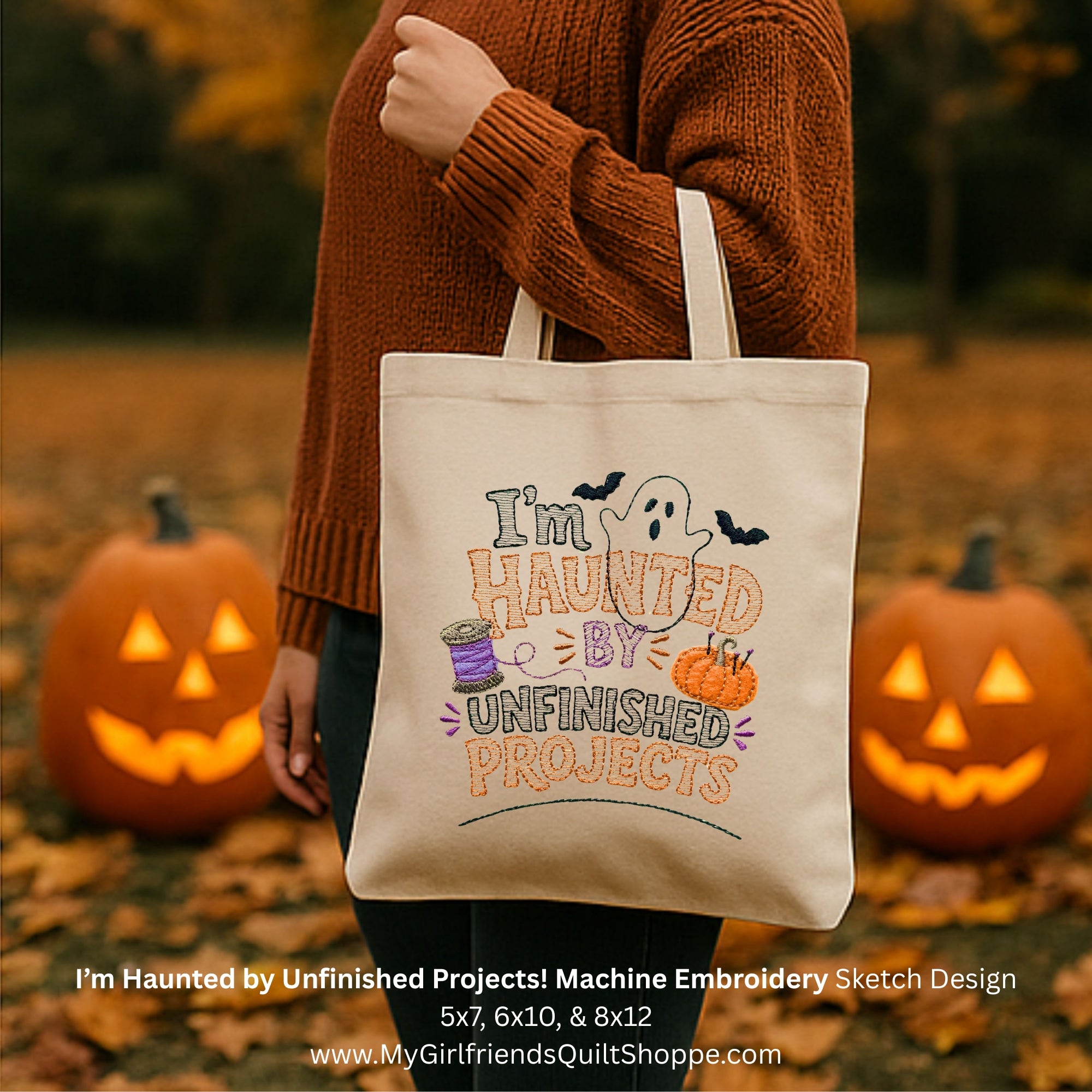 A person in a rust-brown sweater holds a cream canvas tote bag outdoors with jack-o'-lanterns in the background. The tote bag has a machine-embroidered Halloween design that reads 'I'm Haunted by Unfinished Projects' with a ghost, bats, pumpkin, and purple potion bottle.