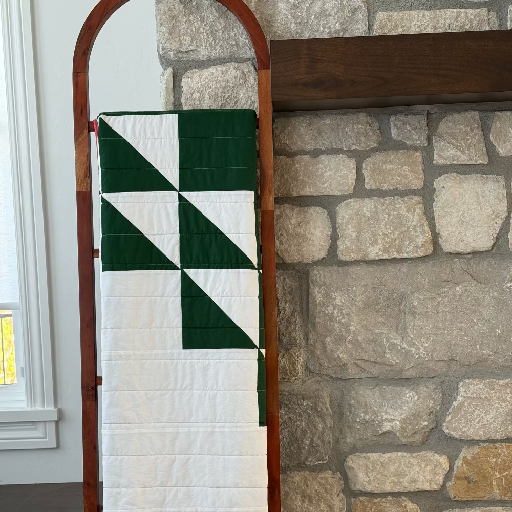 Quilt on a wooden ladder against a stone wall