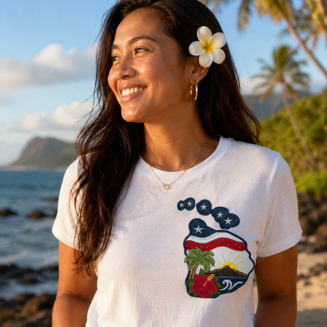 Woman wearing a white t-shirt with a graphic design, standing on a beach with palm trees and ocean in the background.
