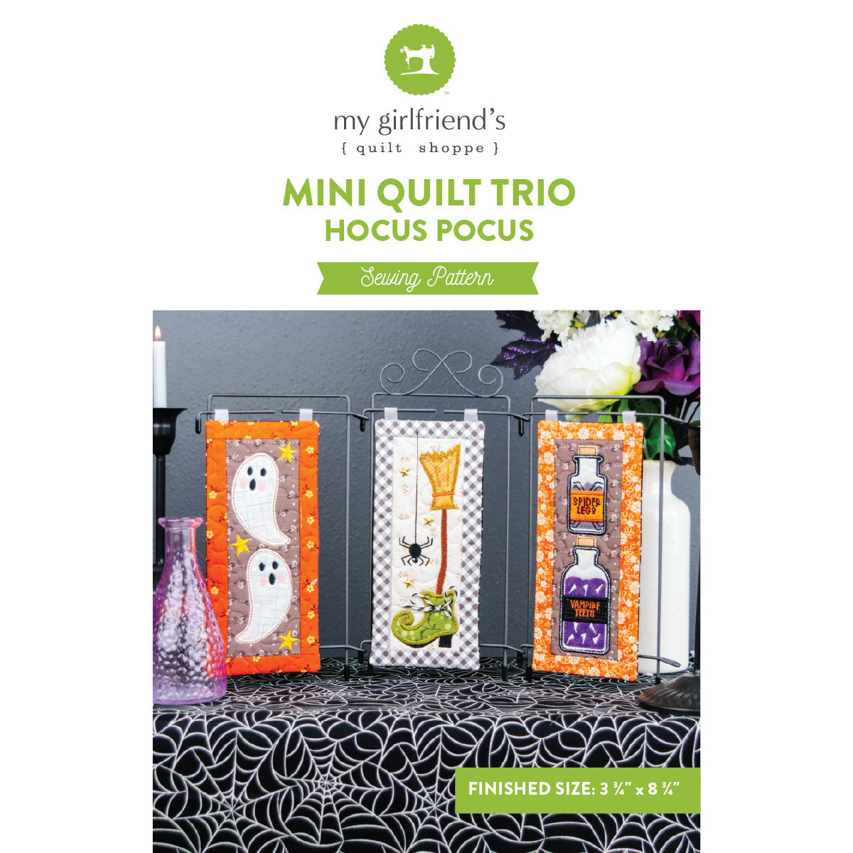 Sewing pattern cover for 'Mini Quilt Trio: Hocus Pocus' by my girlfriend's quilt shoppe, showing three finished Halloween-themed mini quilts displayed on a stand.