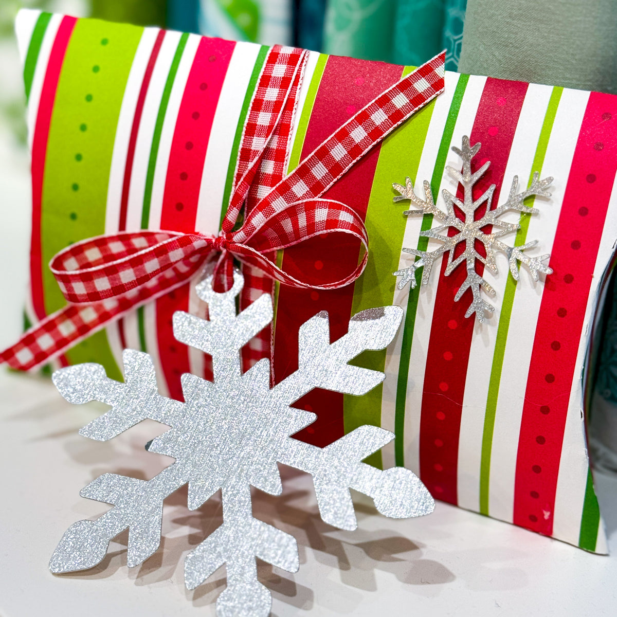 Decorative gift with striped paper, red ribbon, and silver snowflake ornament.