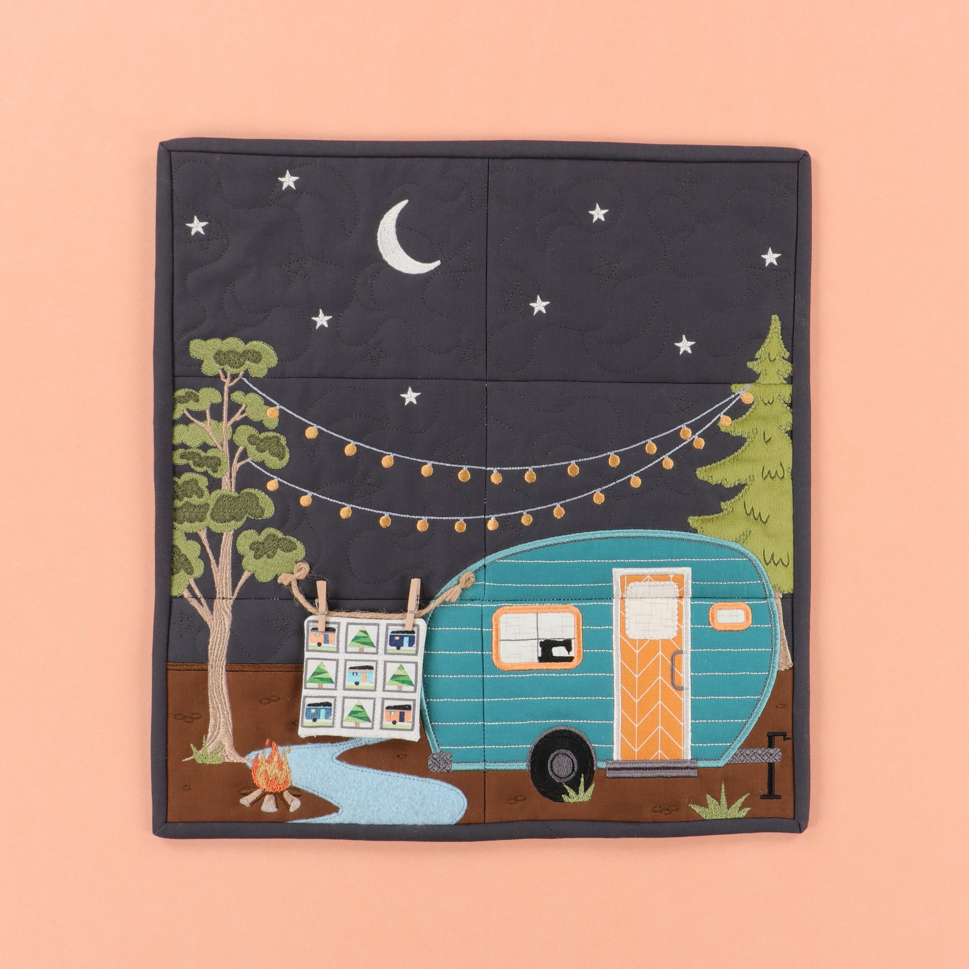 Quilted fabric panel with a camper, trees, and night sky design on a peach background