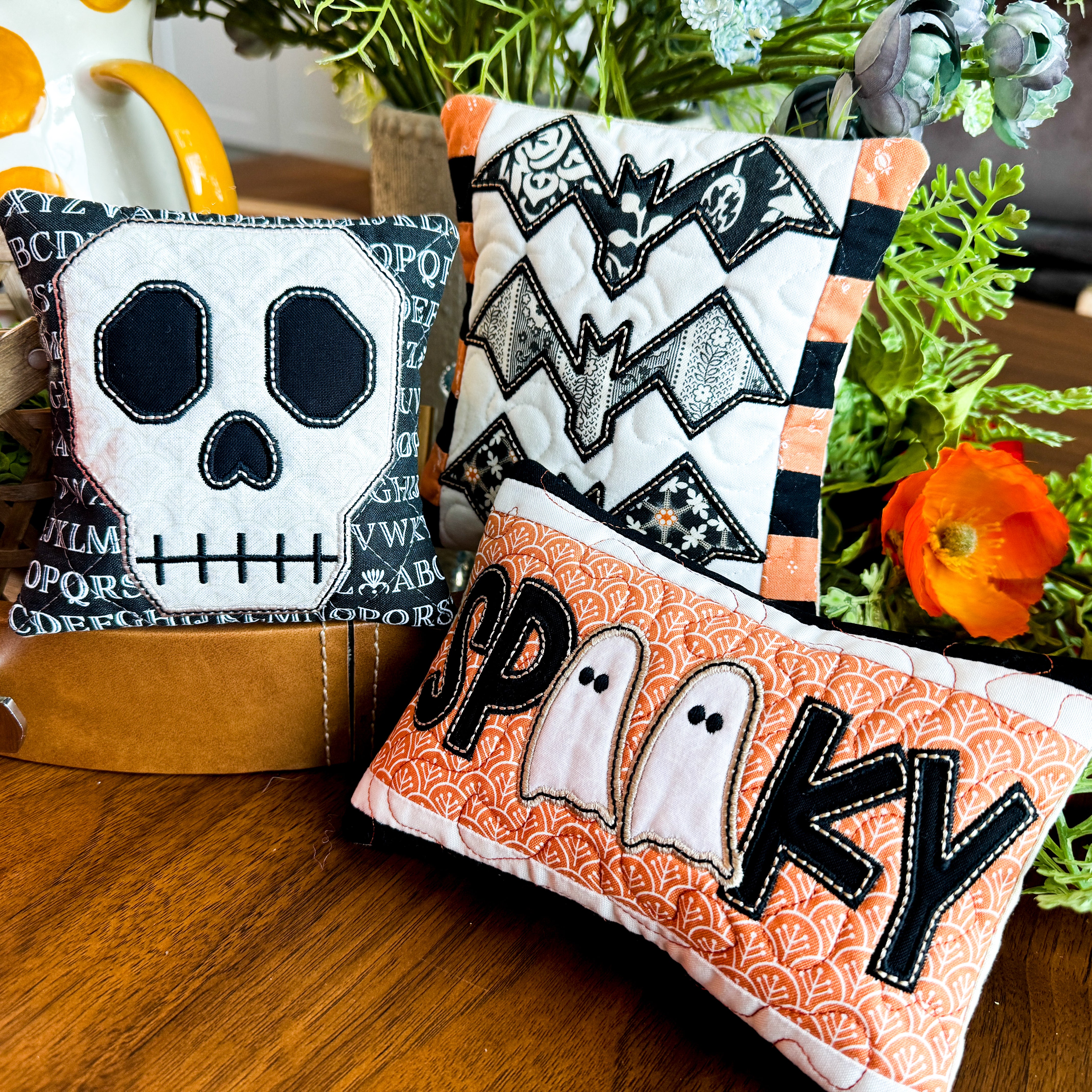 Halloween-themed decorative pillows on a wooden surface with plants in the background