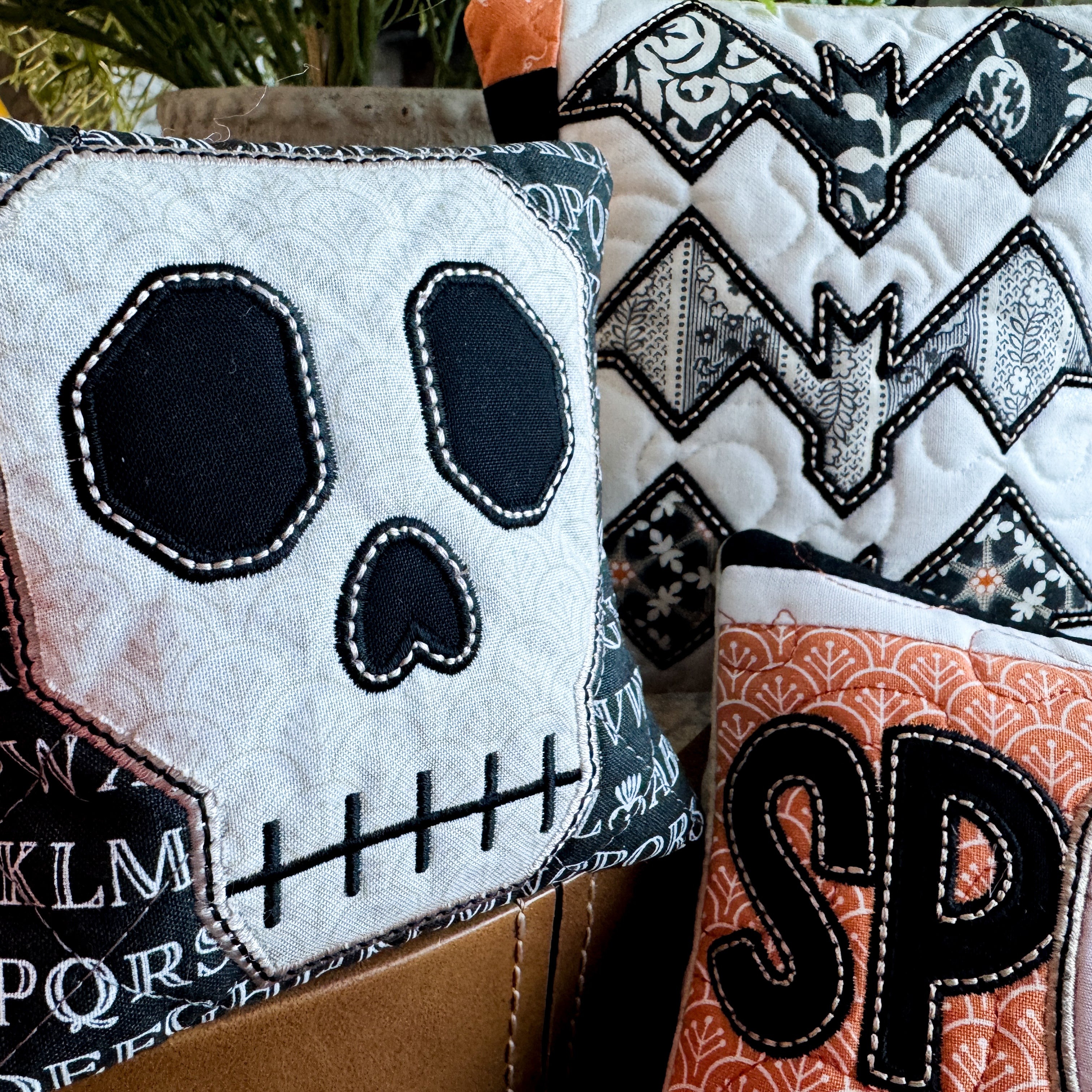 Halloween-themed decorative pillows with skull, bat, and ghost designs.
