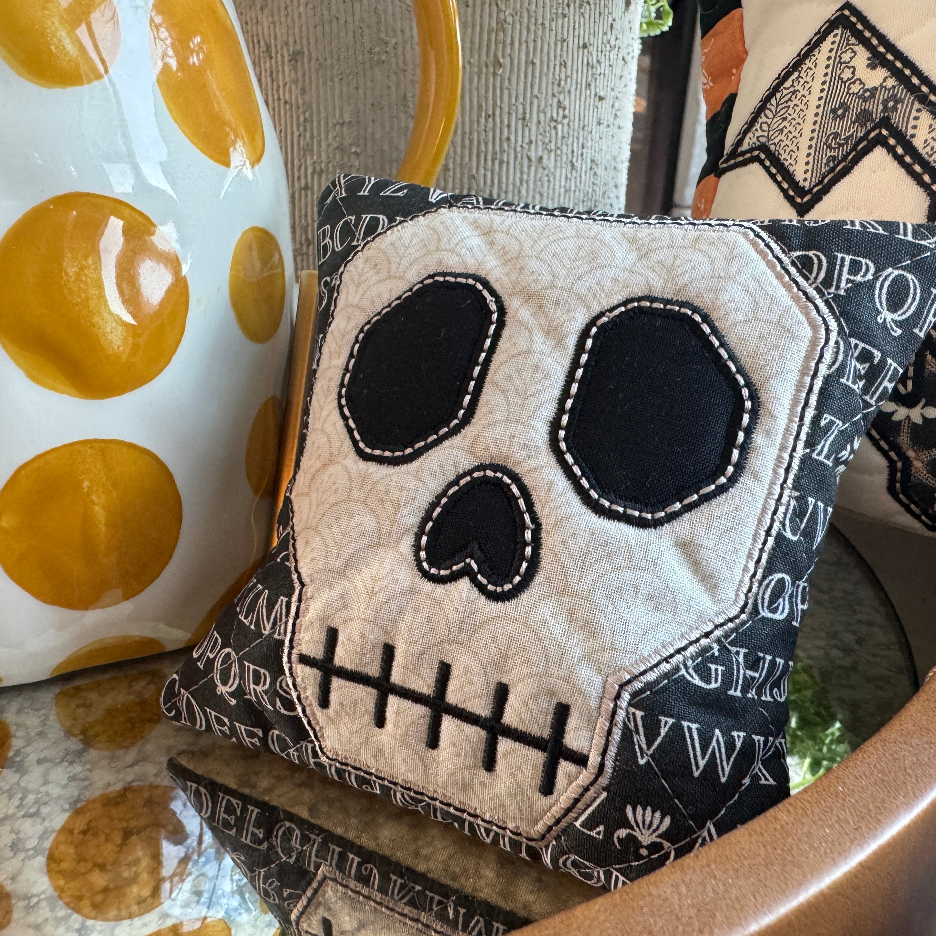 Decorative pillow with skull design on a chair next to a polka dot item.