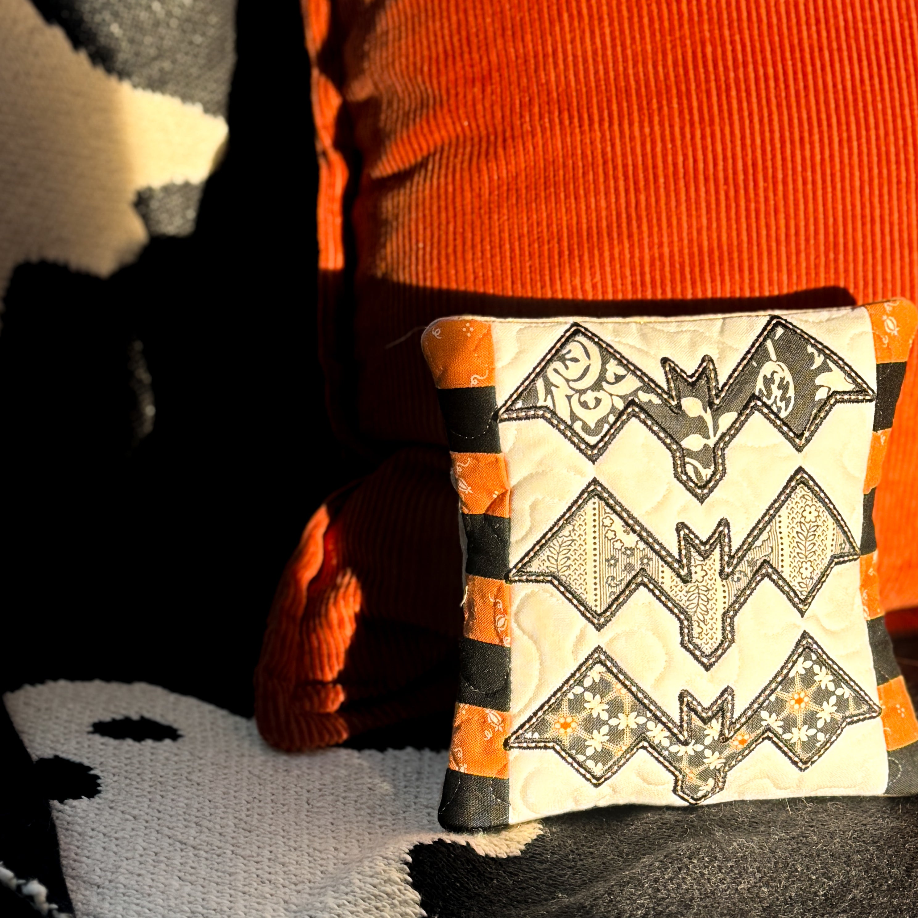 Decorative pillow with bat pattern on a black and orange background