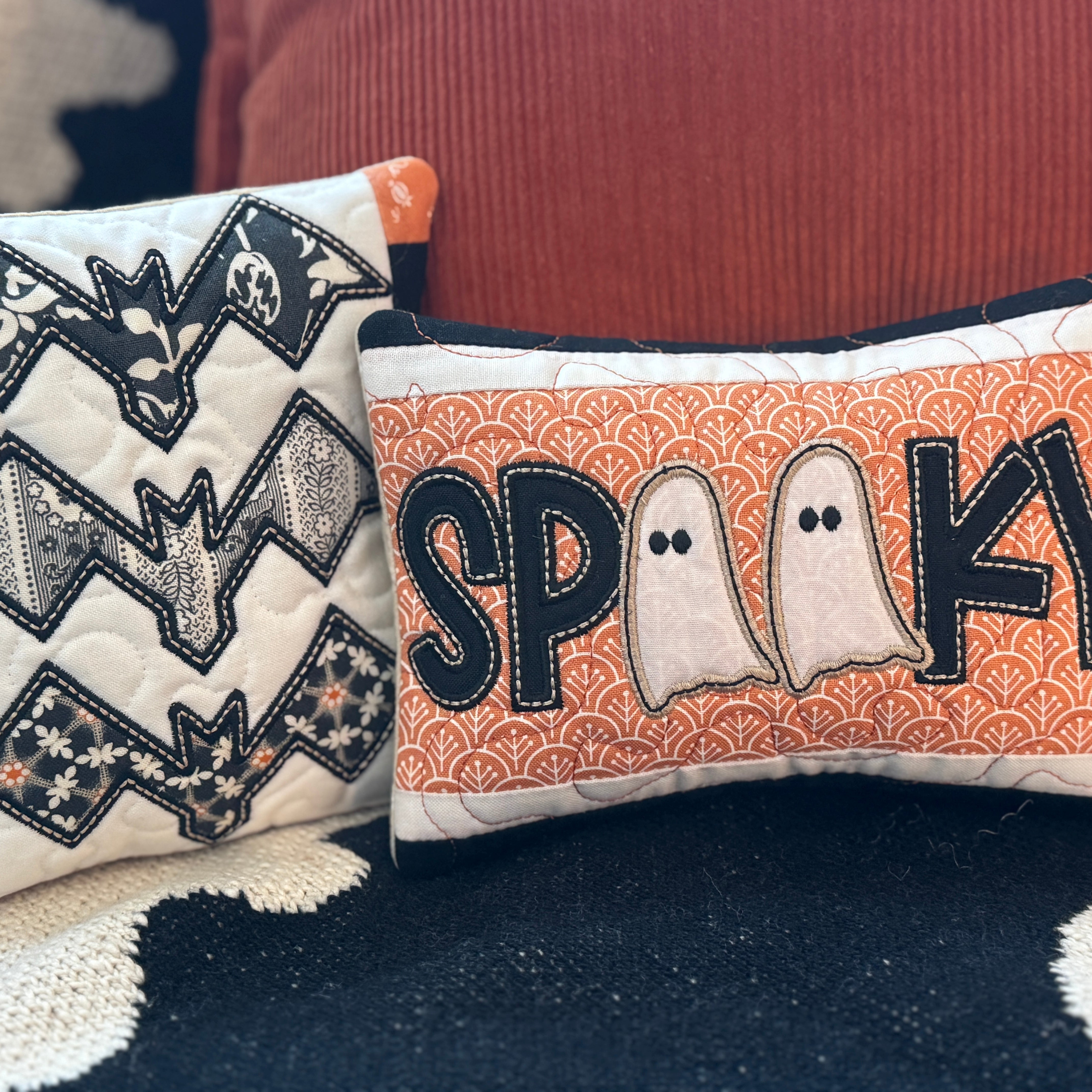 Two Halloween-themed pillows with bat design and 'Spooky' text on a textured surface.