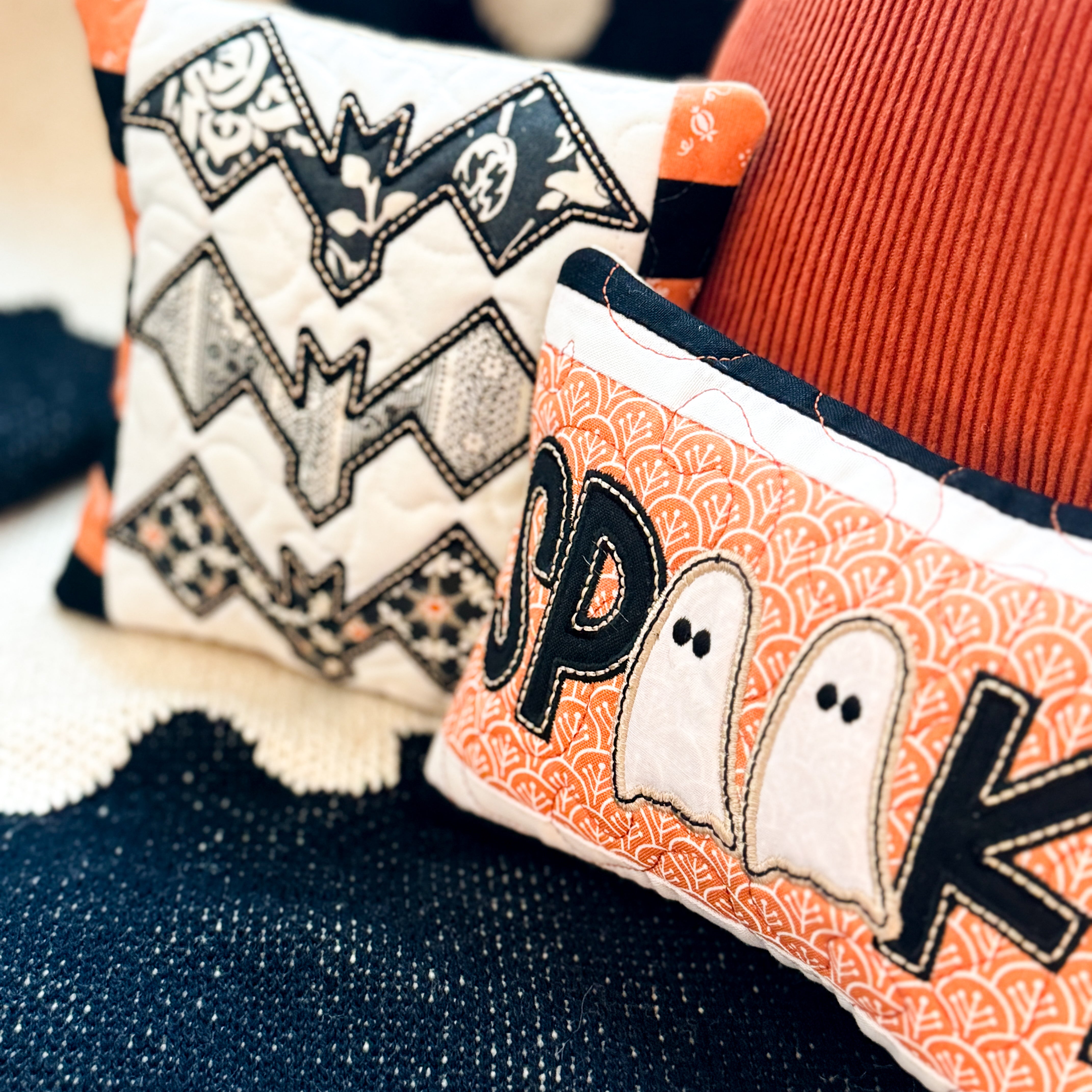 Decorative pillows with Halloween-themed designs on a textured surface.
