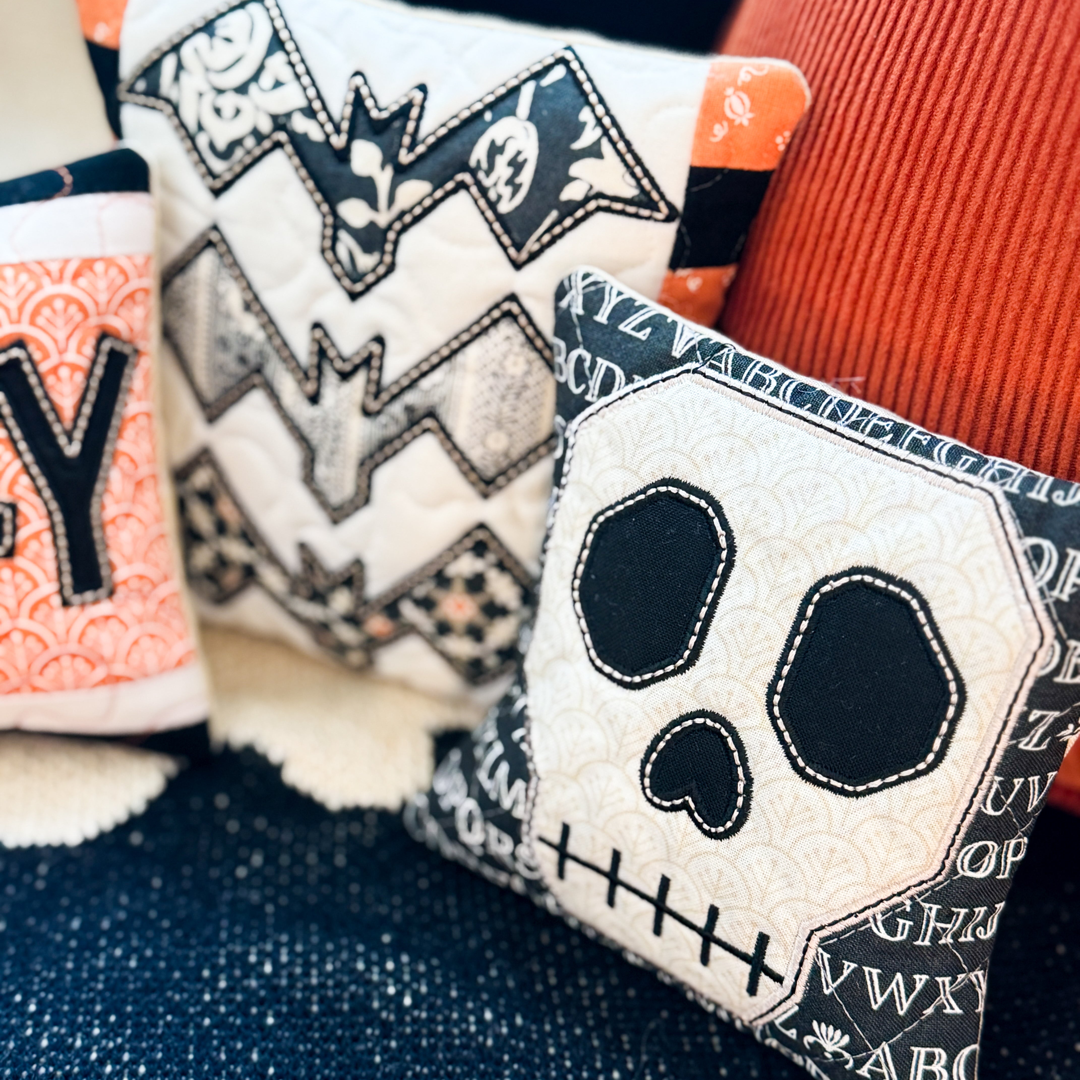 Decorative pillows with Halloween-themed designs on a textured surface.