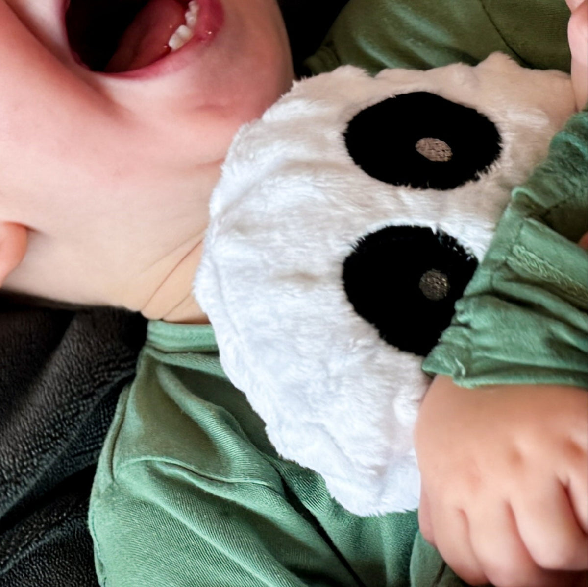 Child wearing a ghost-shaped pillow with a green shirt