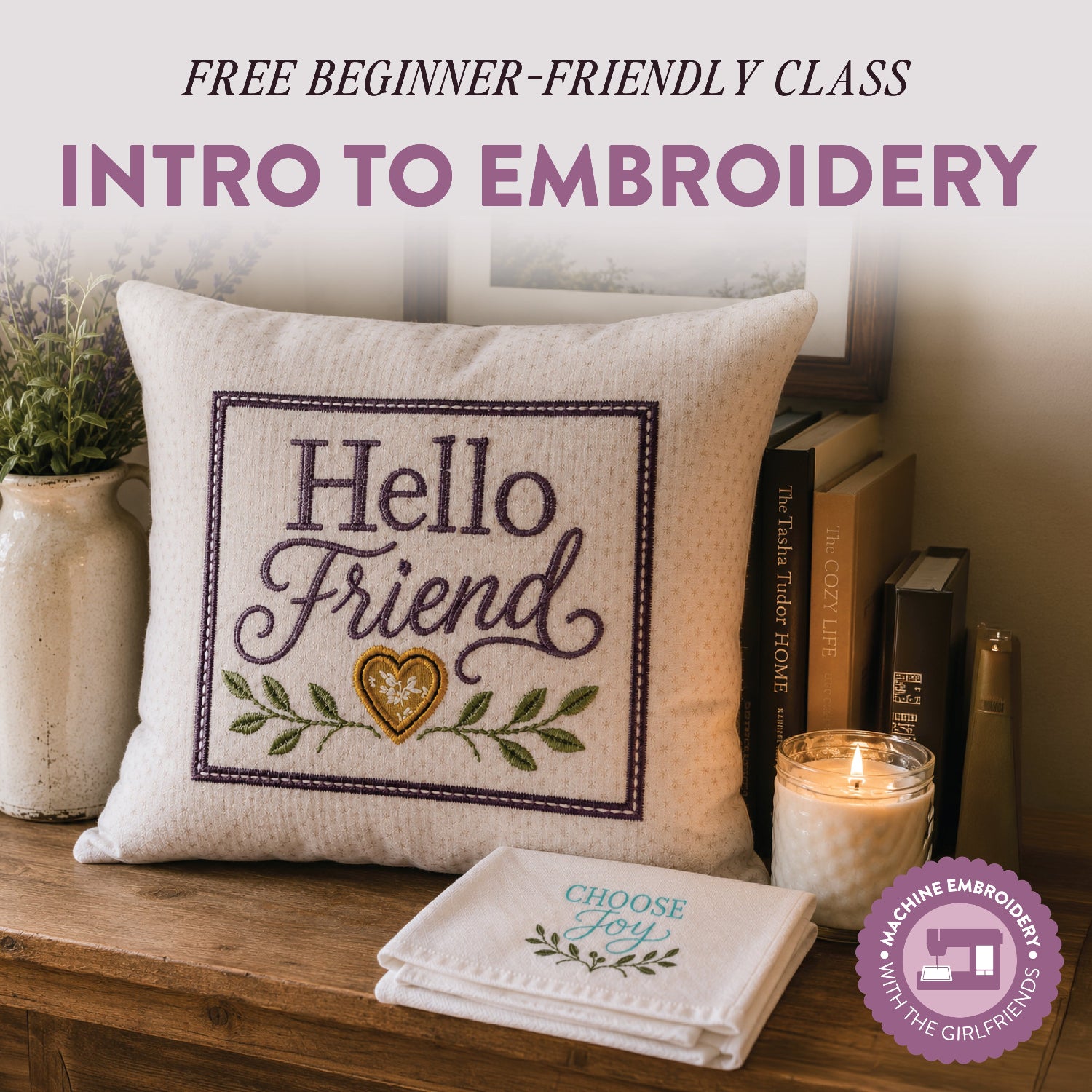A decorative embroidered throw pillow sits on a wooden surface beside a folded matching embroidered cloth, with books, a candle, and a vase in the background. Large text at the top reads 'FREE BEGINNER-FRIENDLY CLASS INTRO TO EMBROIDERY,' and a purple badge in the lower right says 'Machine Embroidery with the Girlfriends.