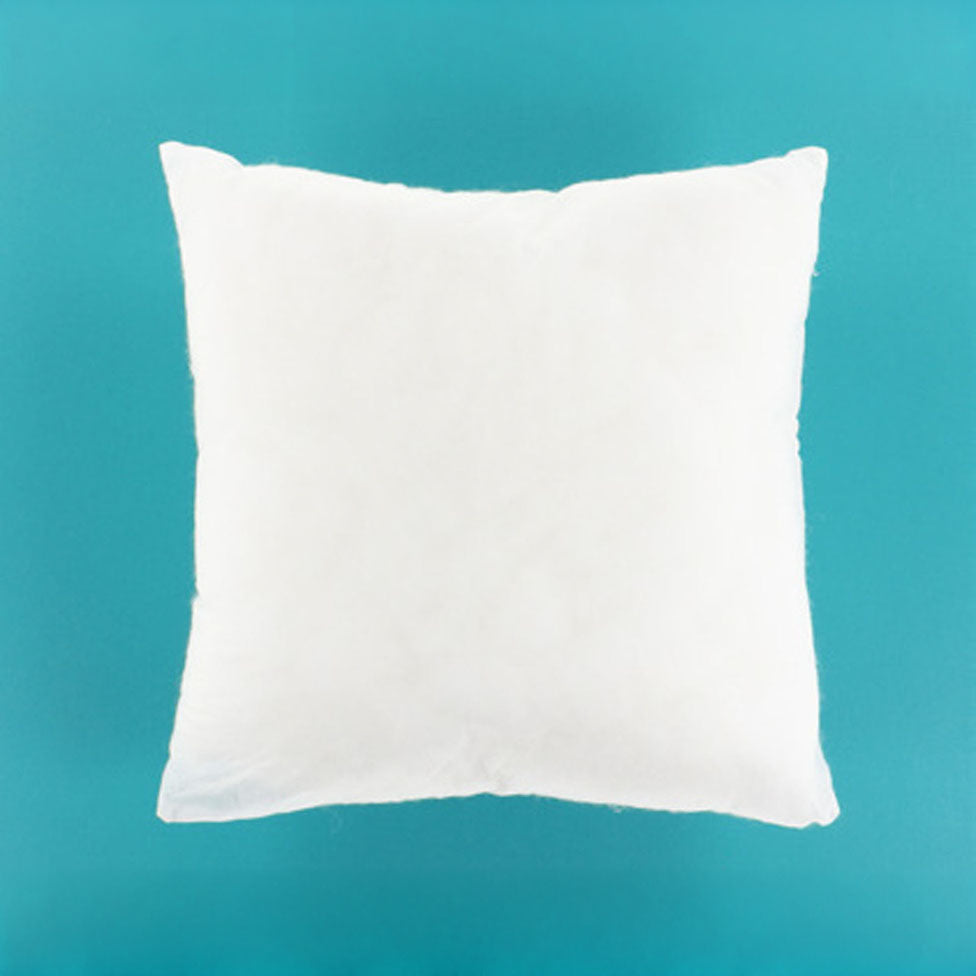 A plain white square throw pillow centered against a solid teal background.