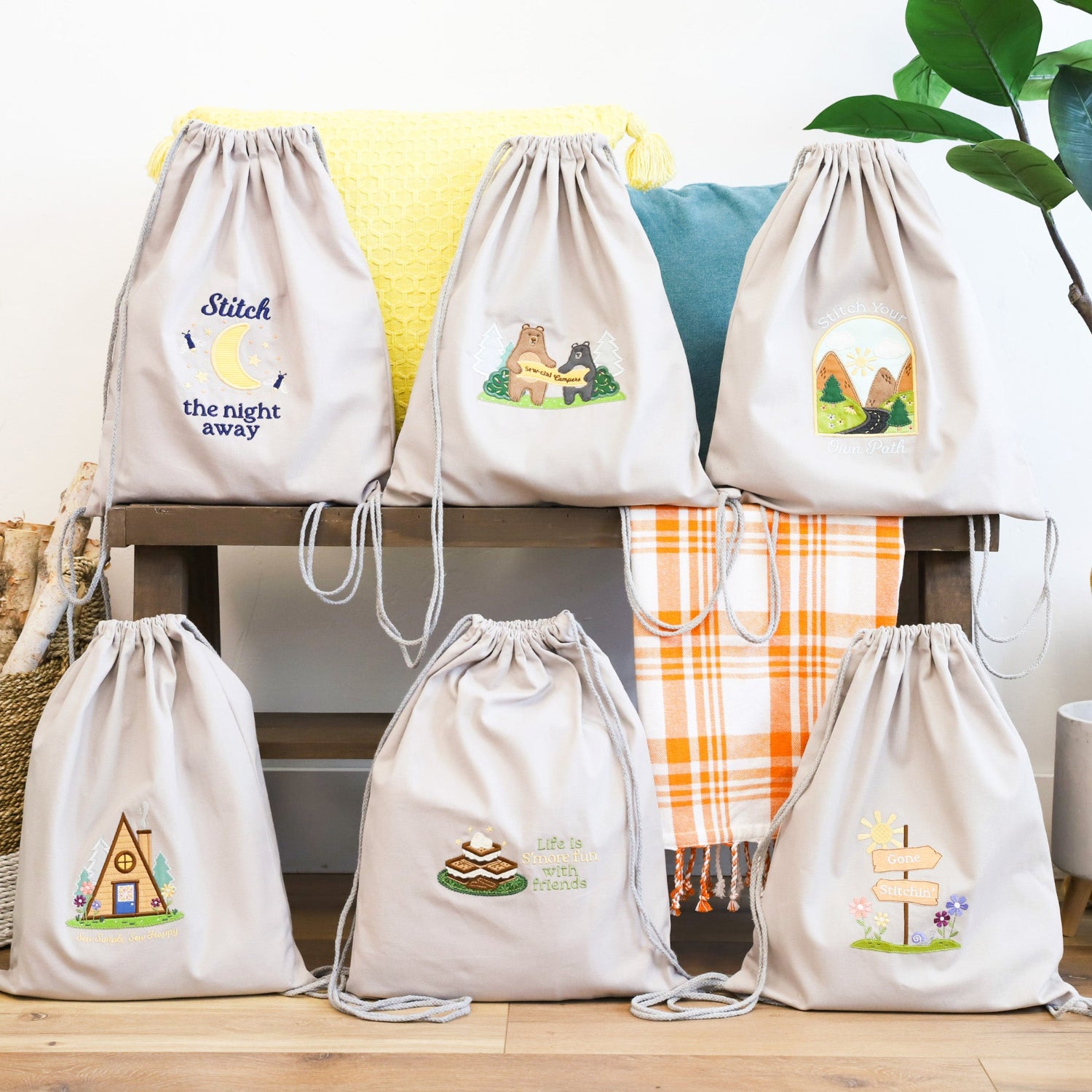 Set of drawstring bags with embroidered designs on a wooden surface.