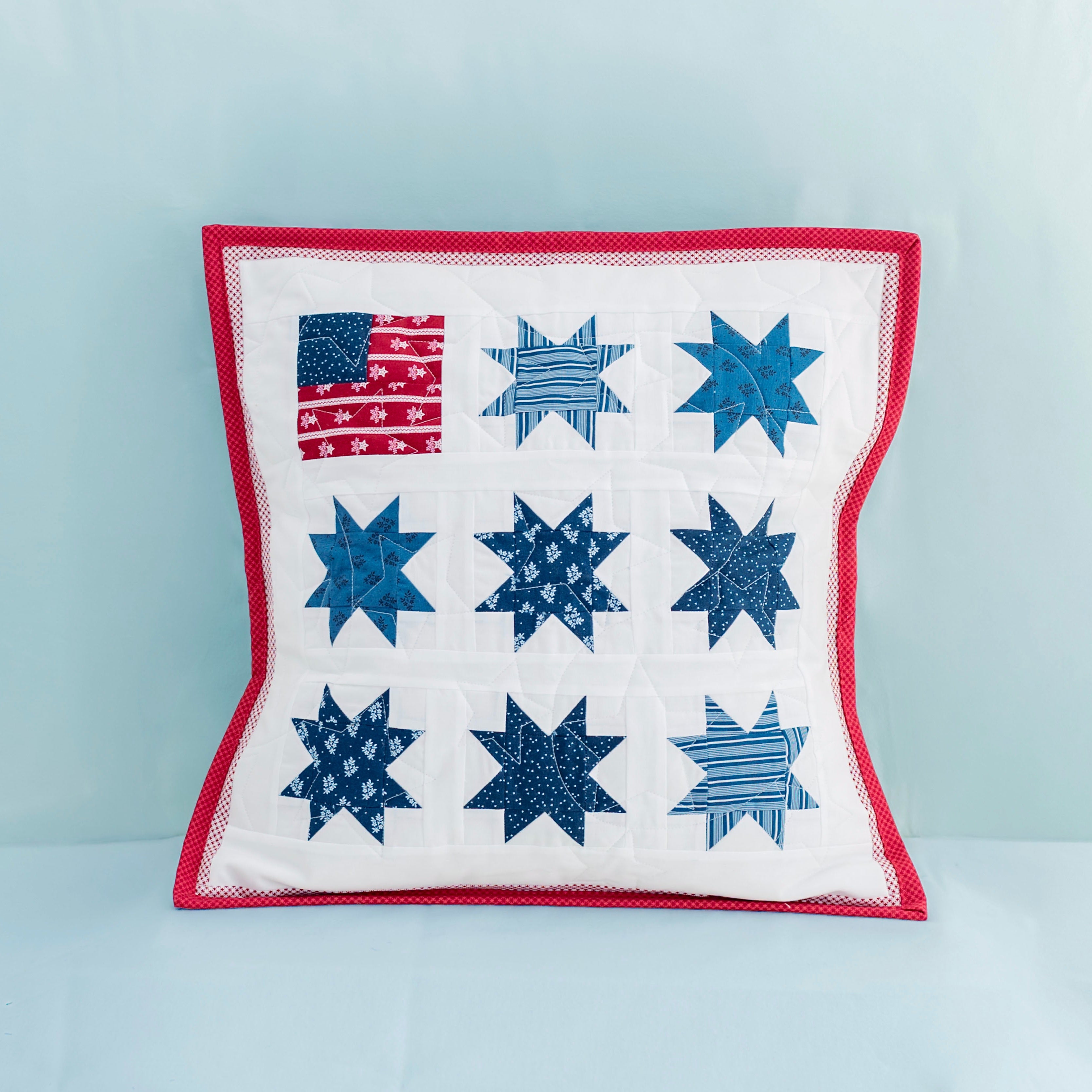 Decorative pillow with star pattern and American flag on a light blue background
