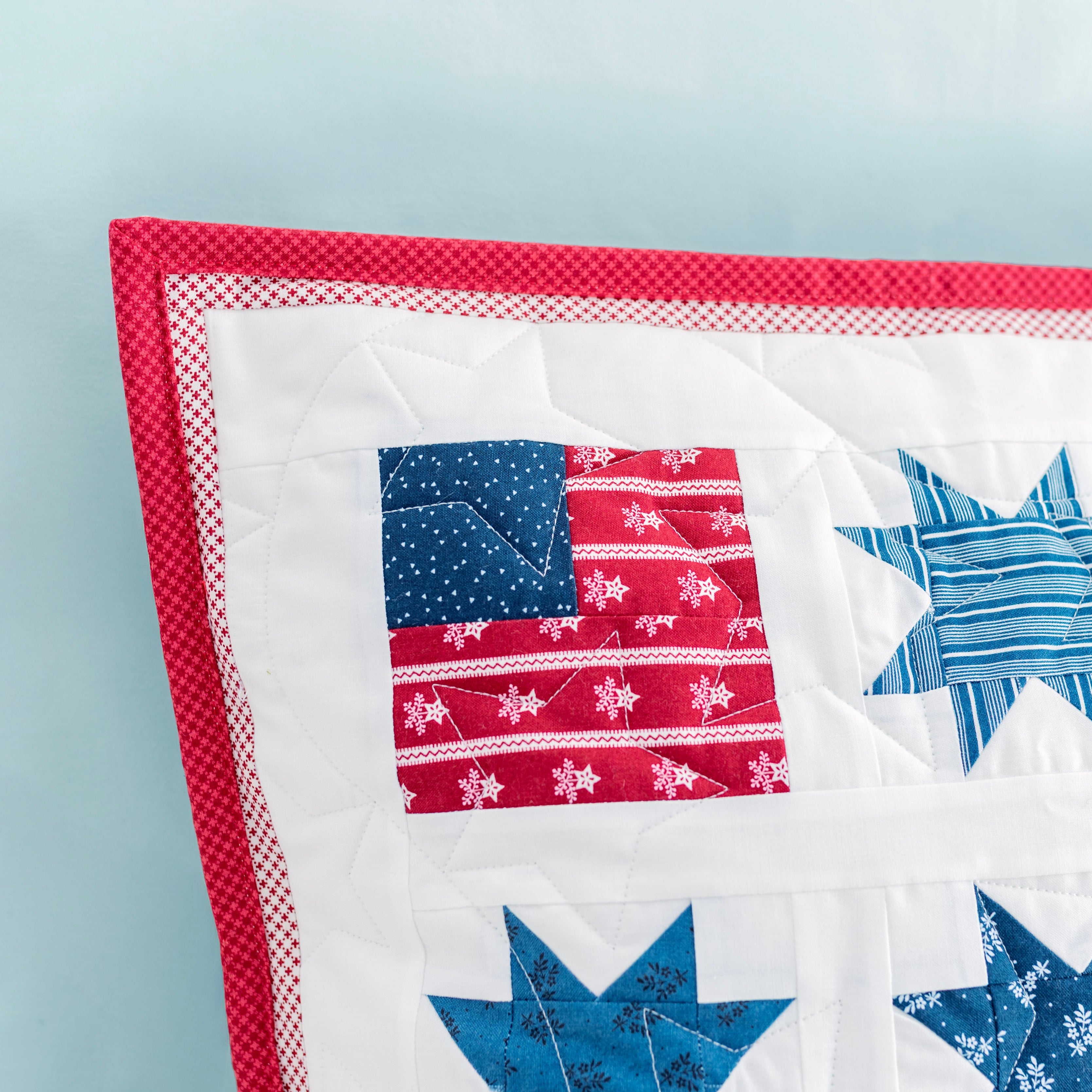 Quilt with star and flag patterns on a light blue background
