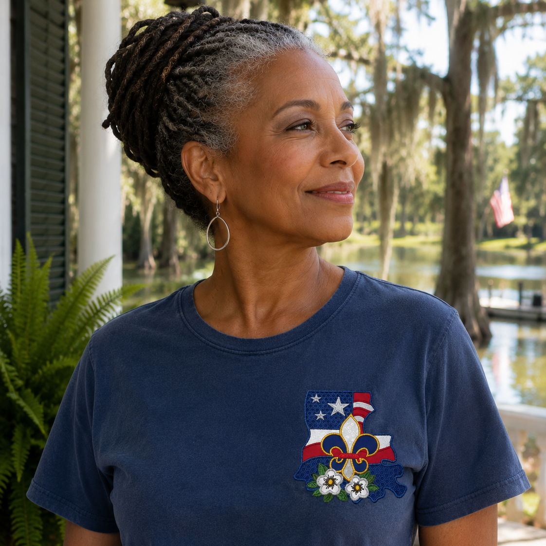 Woman wearing a blue t-shirt with a patriotic design outdoors by a body of water.