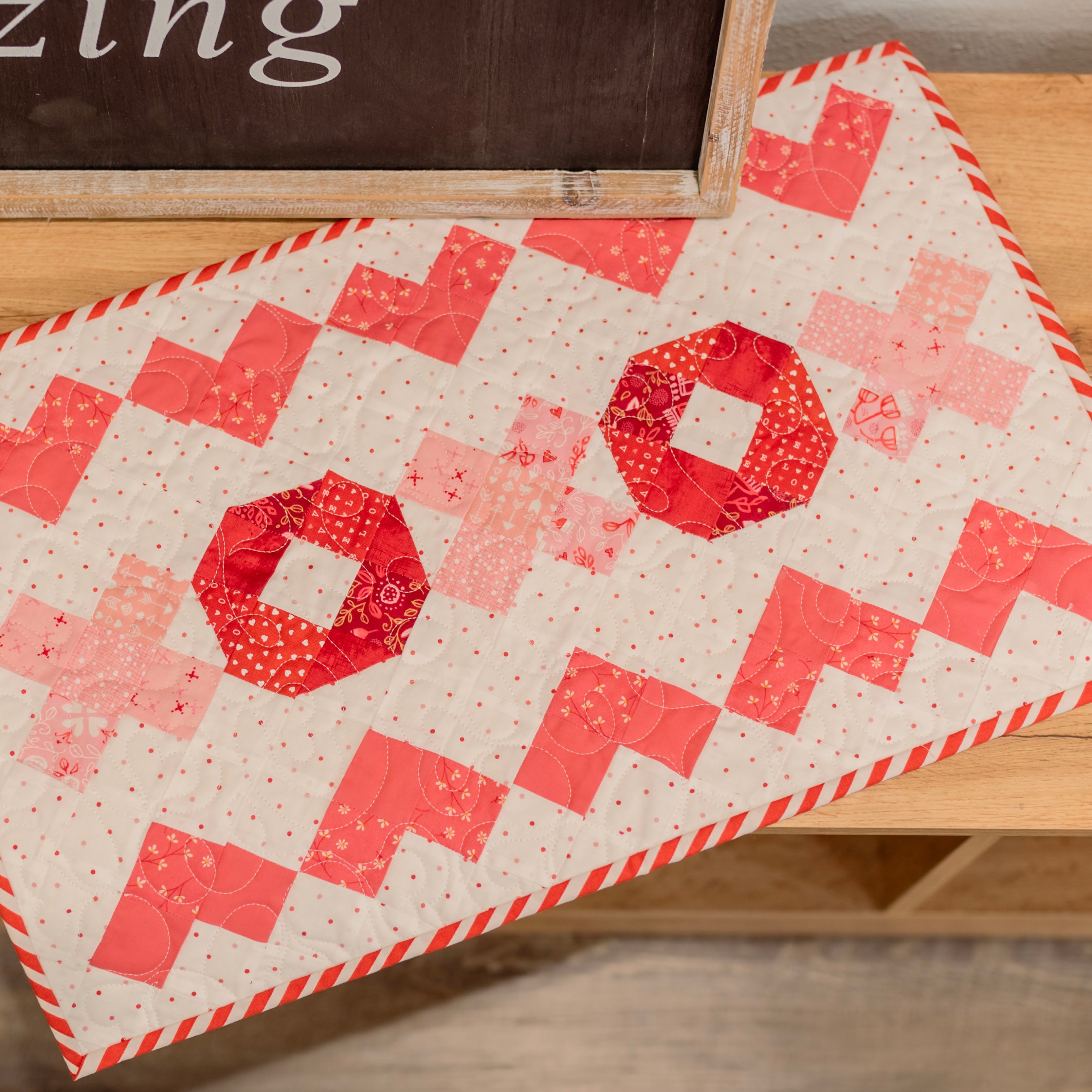 Quilt with red and pink pattern on a wooden surface