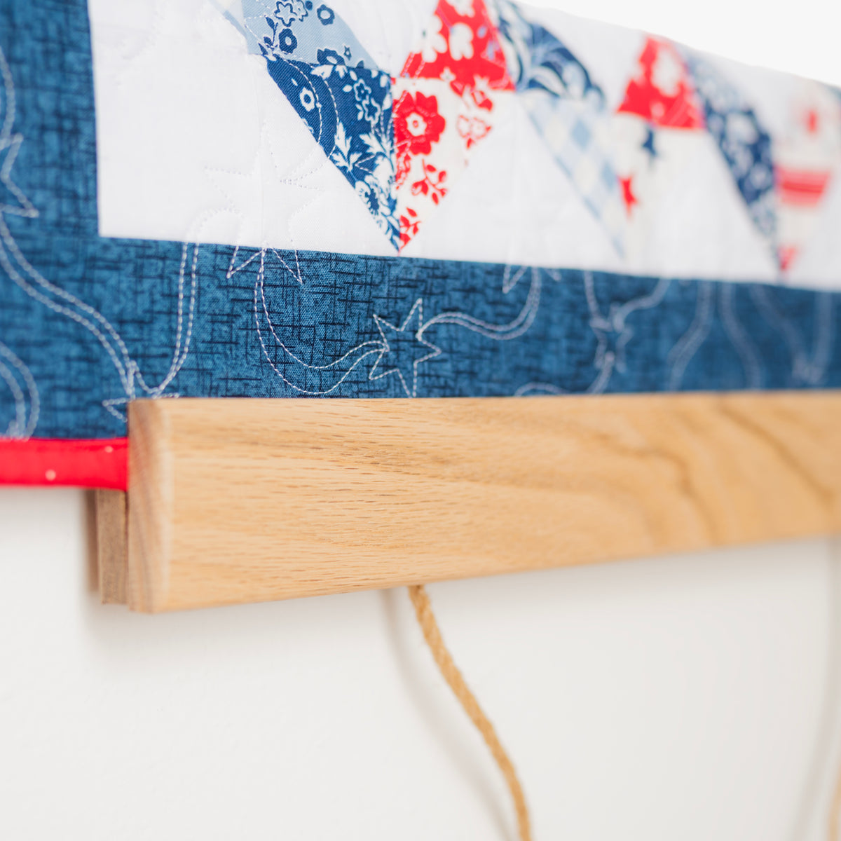 Close-up of a quilt with floral patterns and denim border on a white background 18" wall hanger
