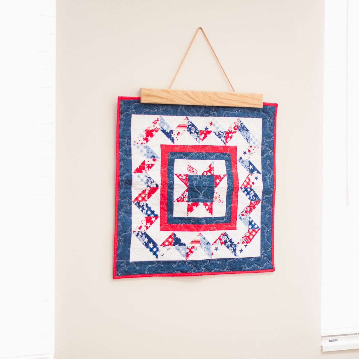 Quilt with a red, white, and blue pattern hanging on a wall. 18" wall hanger