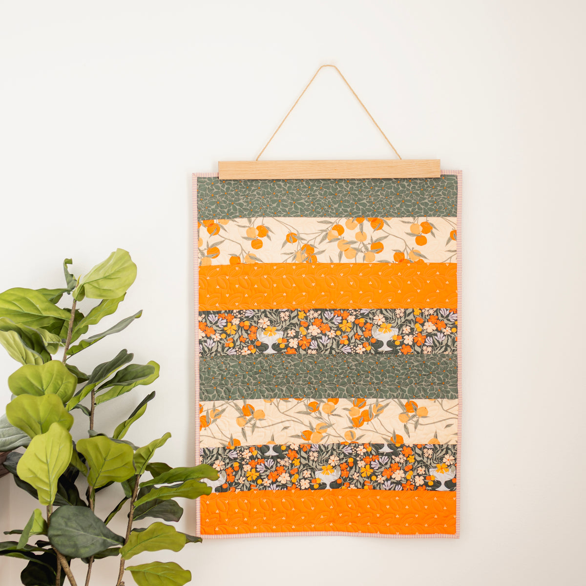 Colorful striped wall hanging with floral patterns on a white wall. 24" wall hanger