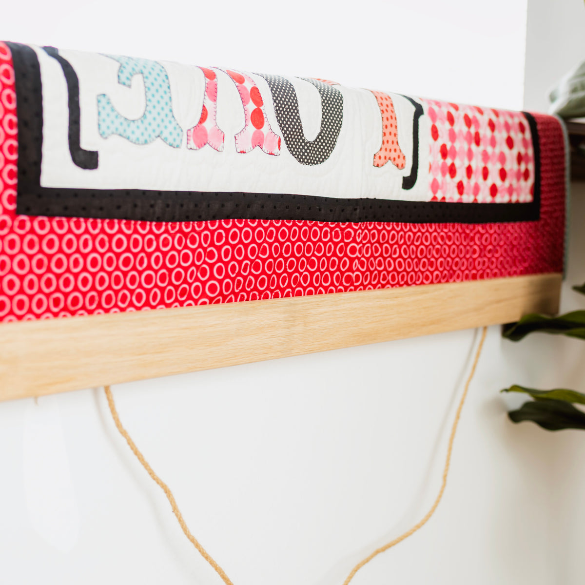Textile art piece with colorful patterns on a wooden frame against a white wall. 36" wall hanger