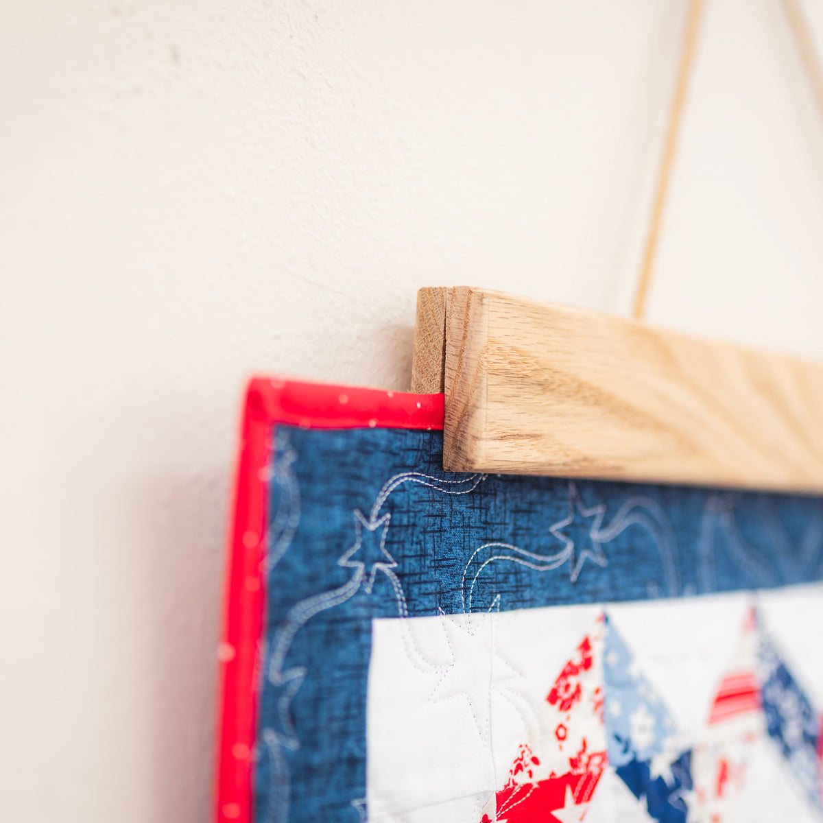 Fabric patch with red, white, and blue design hanging on a wooden frame against a light background 18" wall hanger
