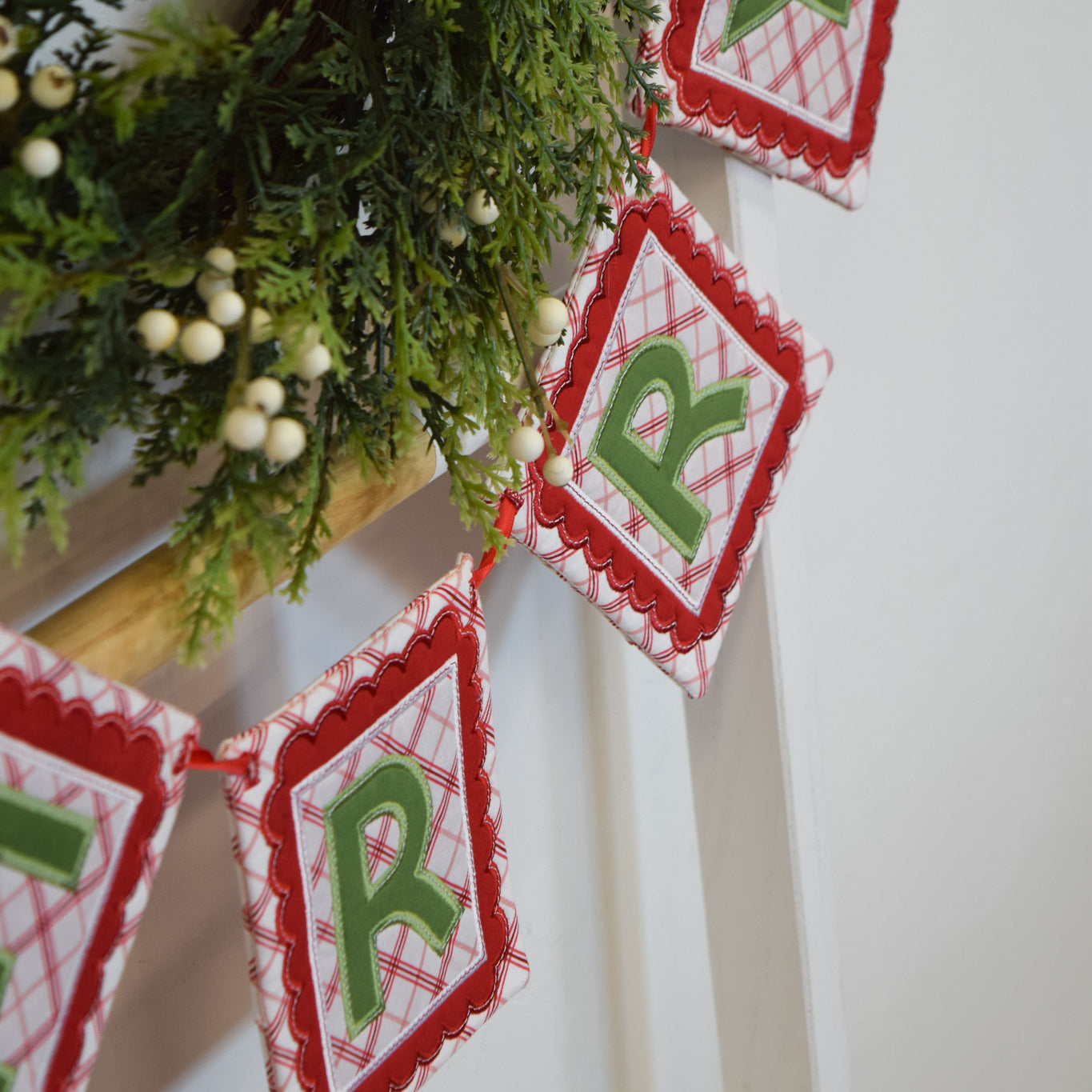 Christmas-themed banner with red and green triangles hanging against a white wall.