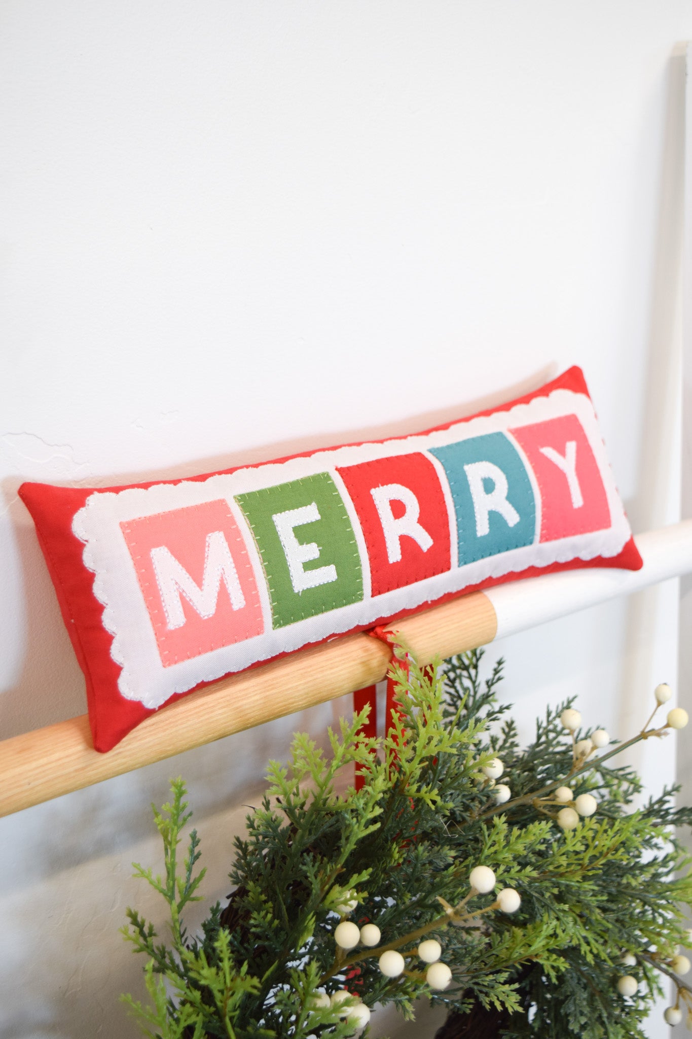 Decorative pillow with 'MERRY' in colorful letters on a white background