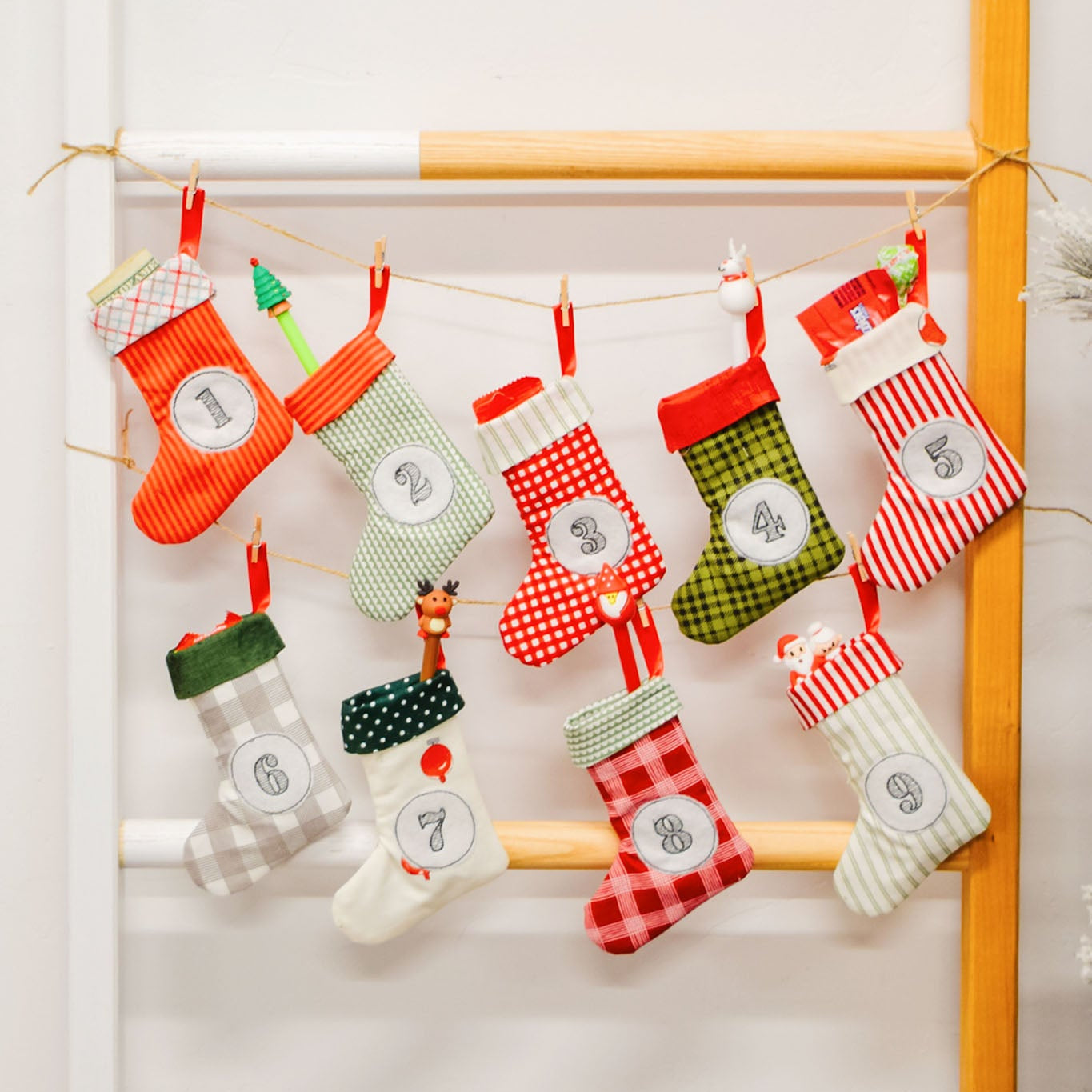 Decorative Christmas stockings with numbers hanging on a rack against a white wall.