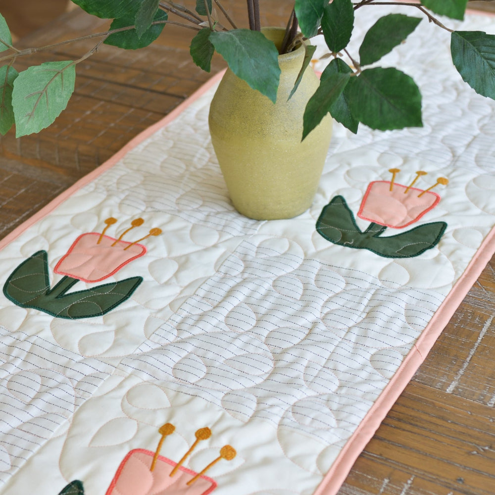 Quilted table runner with floral design on a wooden surface