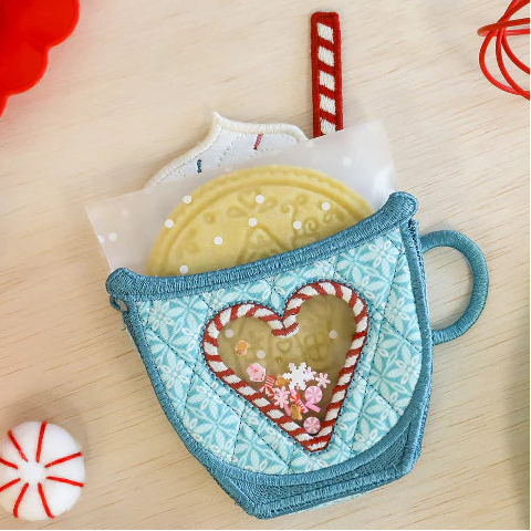 Decorative mug with heart-shaped cookie design on a wooden surface