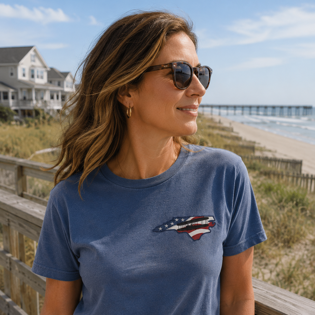 Woman wearing a blue t-shirt with a graphic design on a beach boardwalk.
