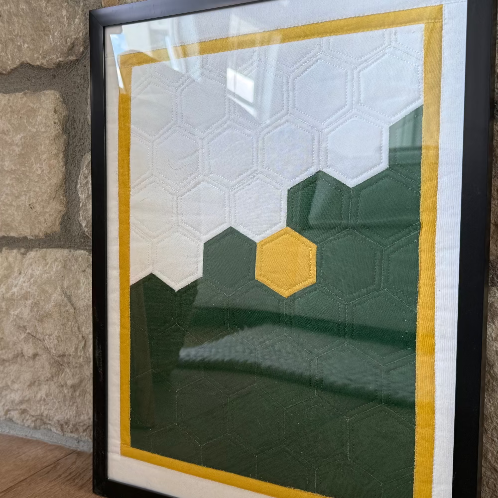 Framed geometric art piece leaning against a stone wall.