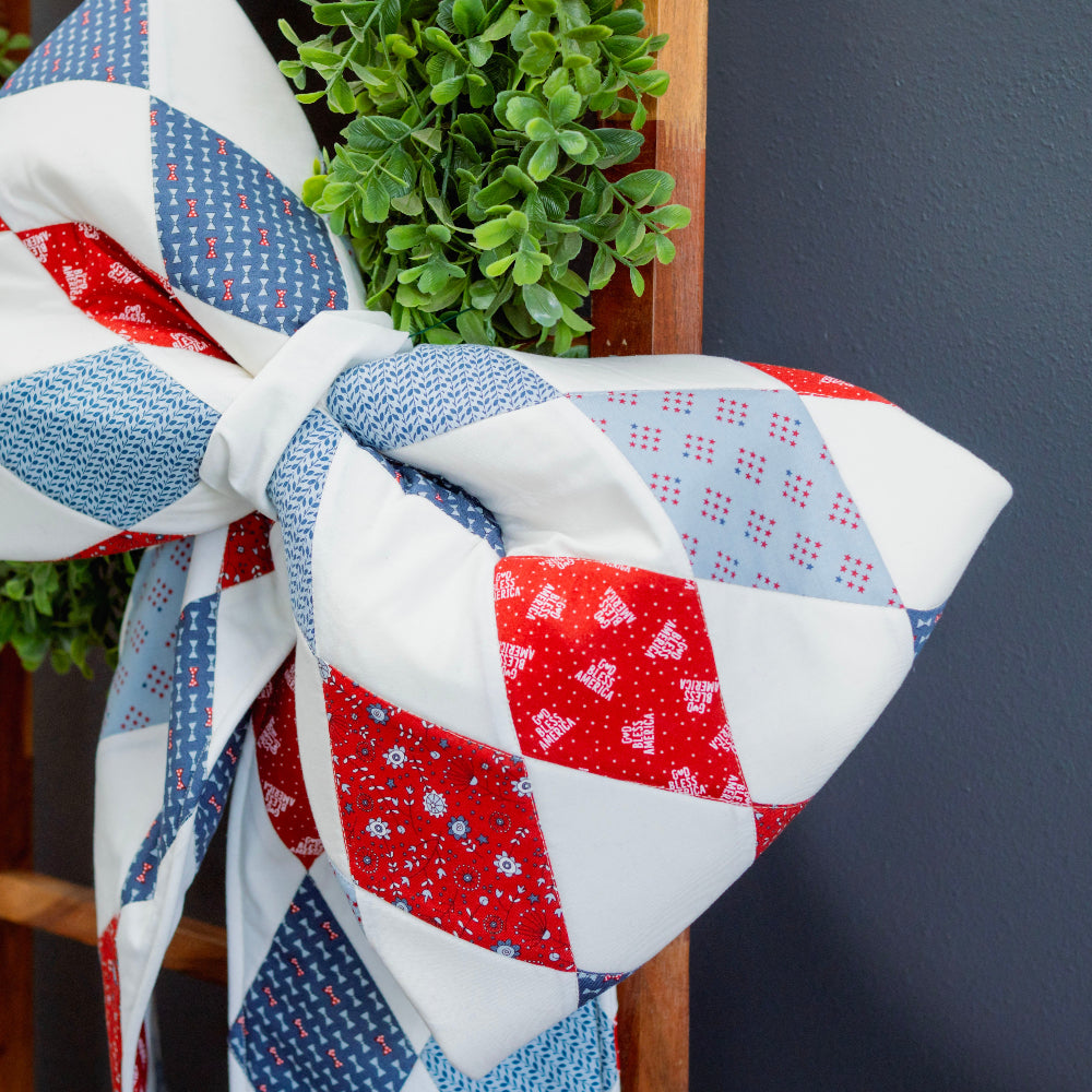 Patchwork towel with red, white, and blue pattern draped over a chair against a dark wall.
