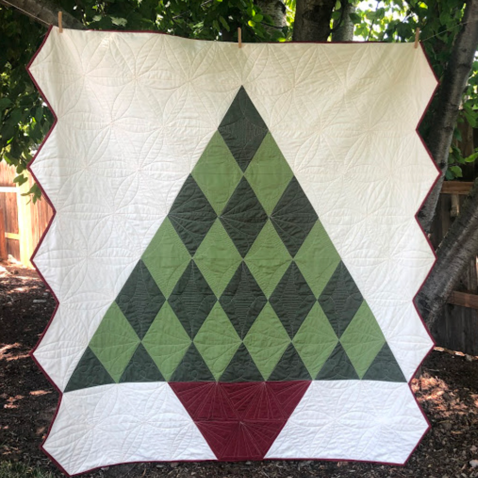 Quilt with green and red diamond pattern hanging outdoors