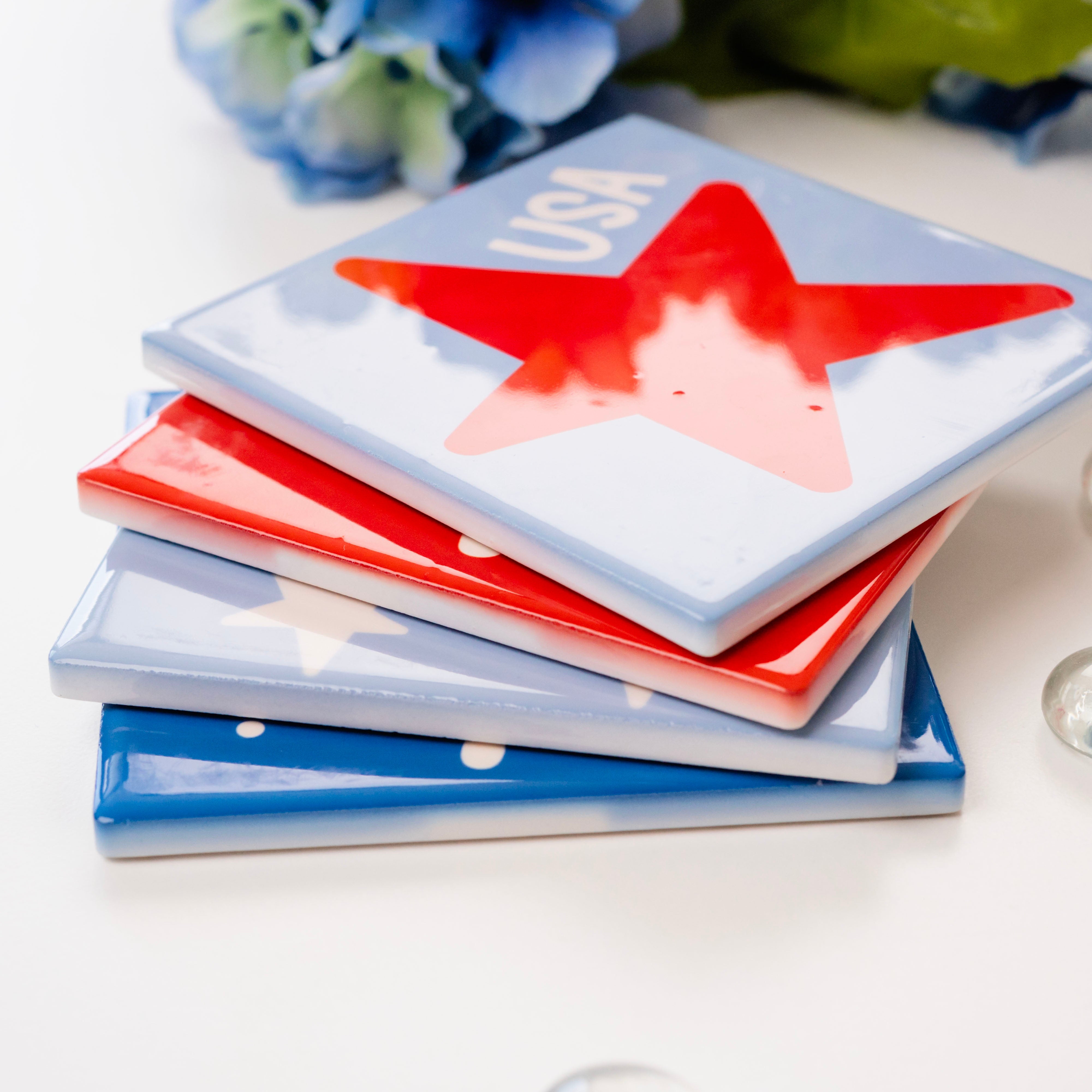 Stack of colorful coasters with a firework design on a white surface with bubbles and flowers.