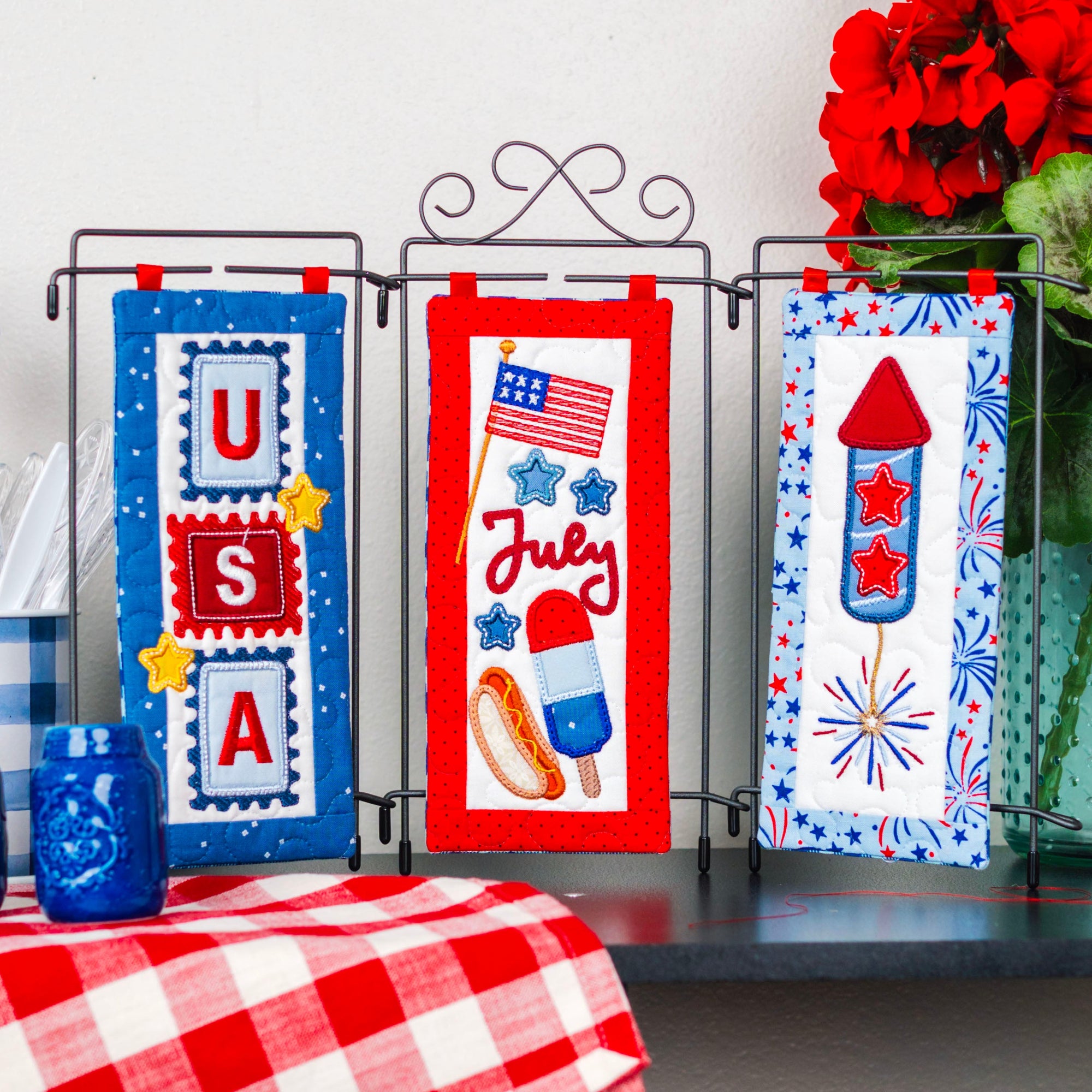 Decorative wall hangings with patriotic designs on a stand against a white wall.