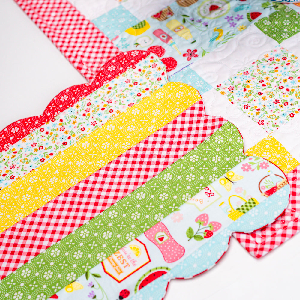 Colorful patchwork table runner with floral and checkered patterns on a white surface.