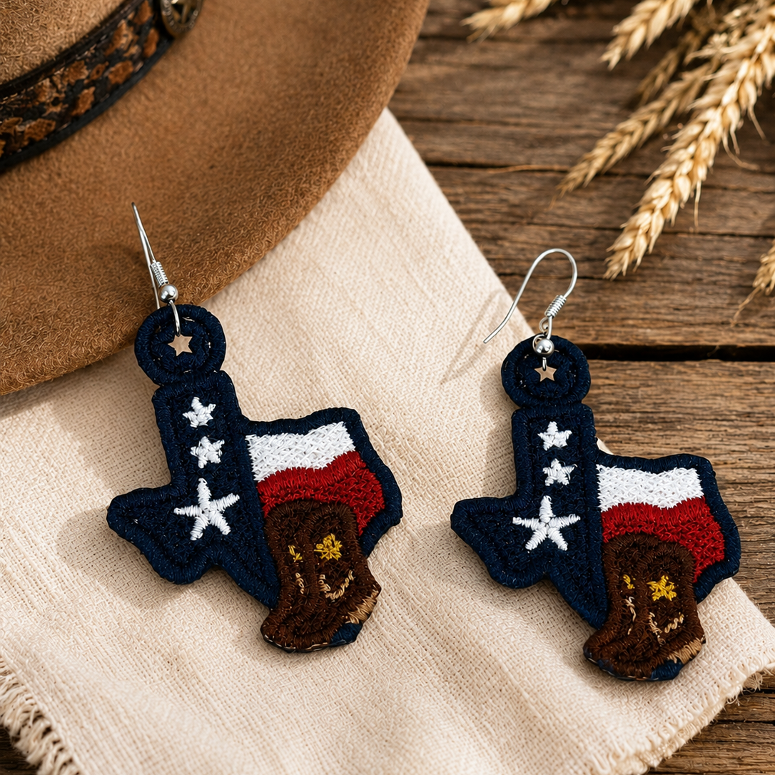 Texas-shaped earrings with American flag design on a wooden surface with a hat and wheat.